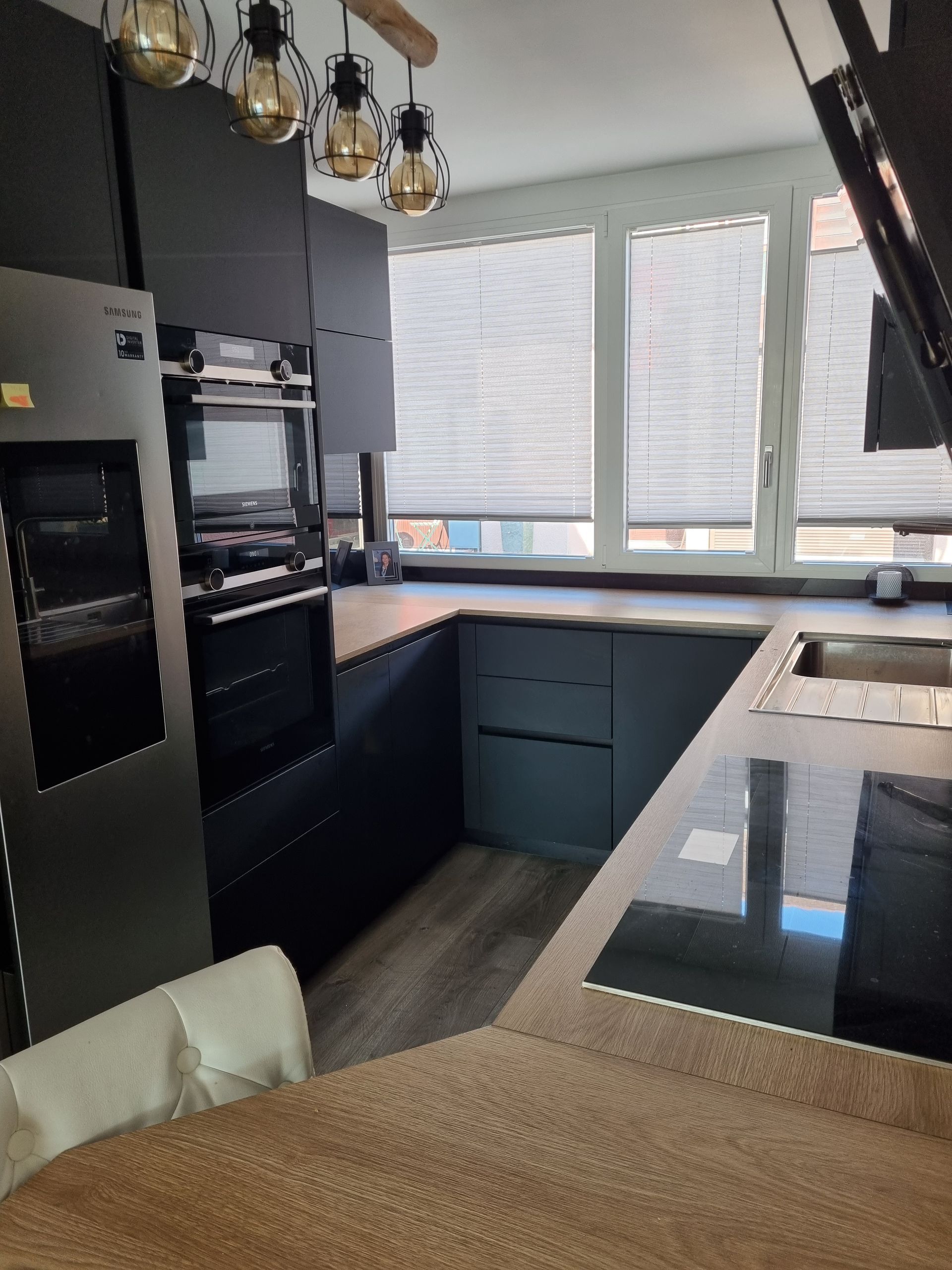 Cuisine moderne gris foncé avec électroménager, placards et fenêtre.