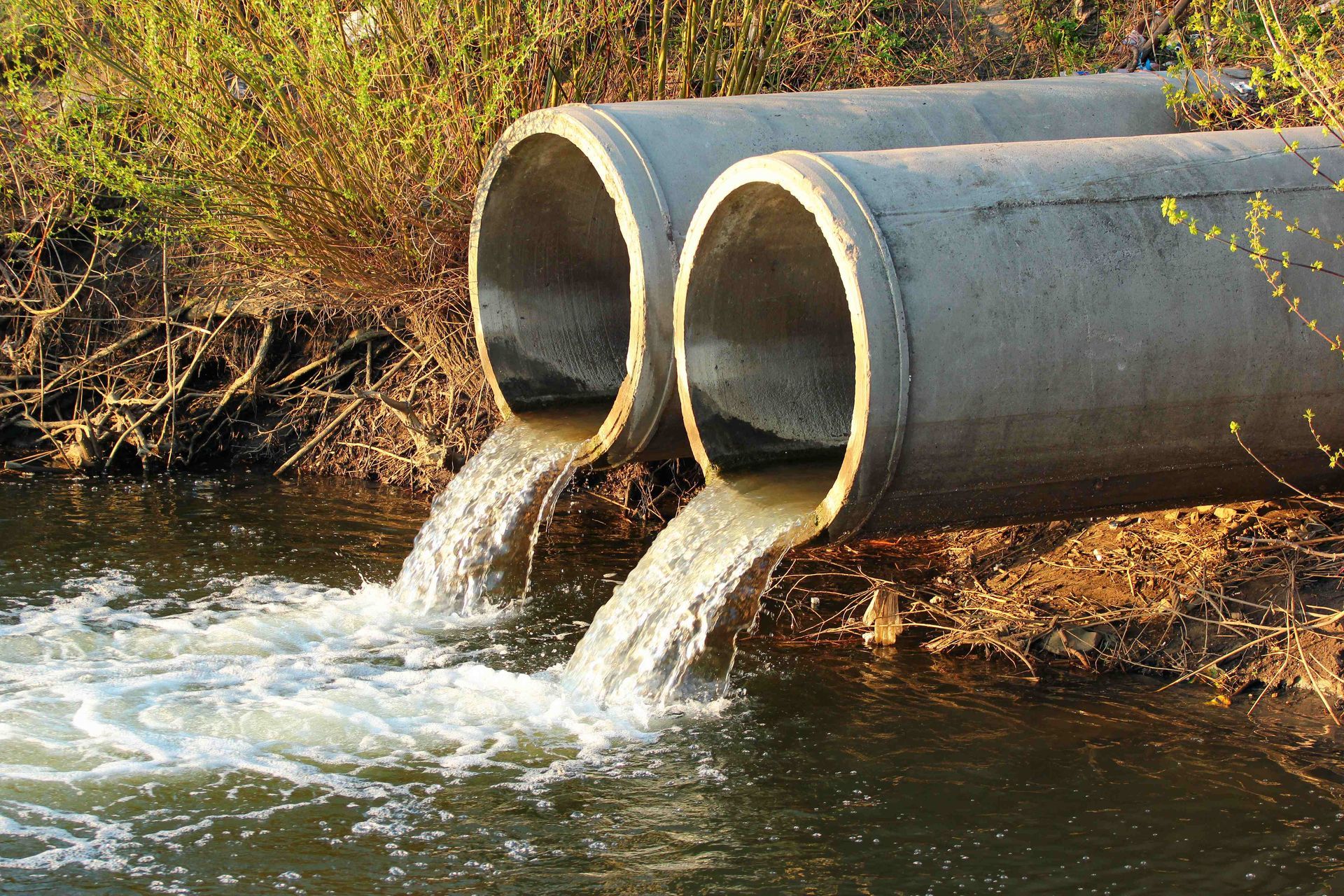 two pipes are pouring water into a river