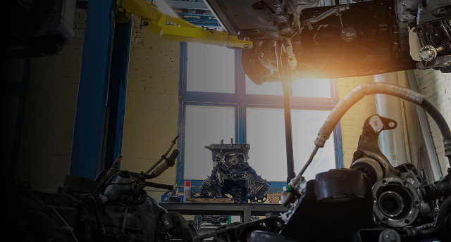 An engine sits in a repair shop. Tools and car parts surround it. | Doran-King Garage Inc