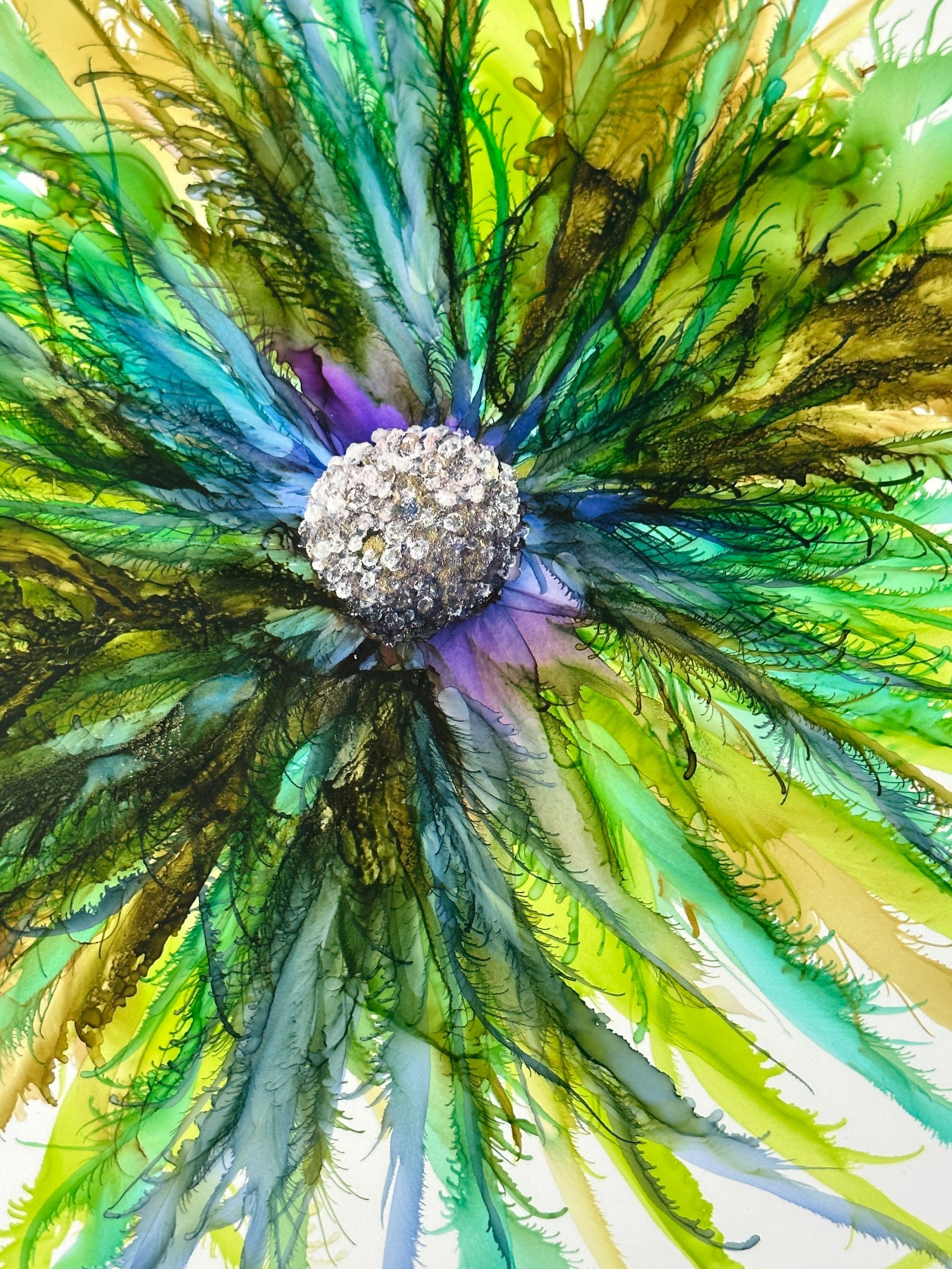 A close up of a colorful flower with a rhinestone center.