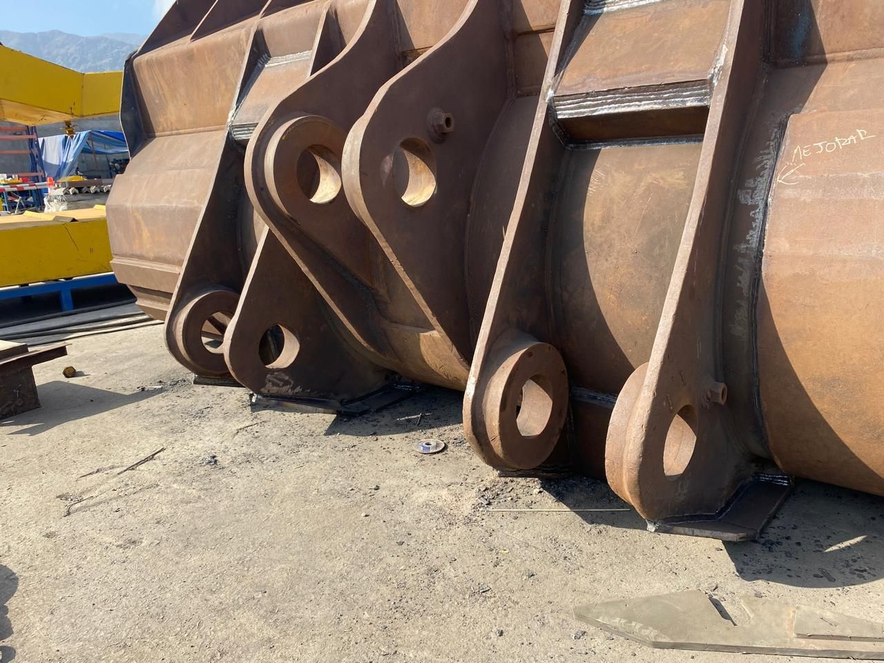 Primer plano de grandes cubos de metal oxidado con agujeros en forma de ojos, probablemente equipos de construcción.