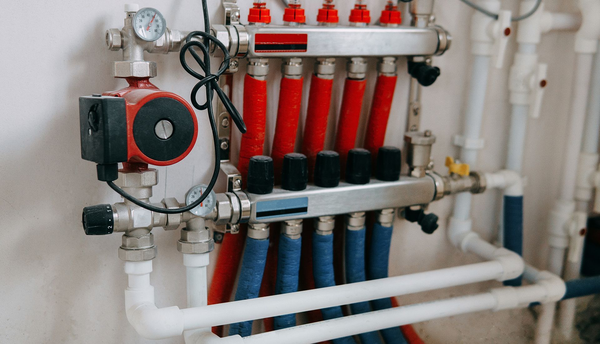 Pipes and valves of a radiant heating system, with red and blue tubes connected.