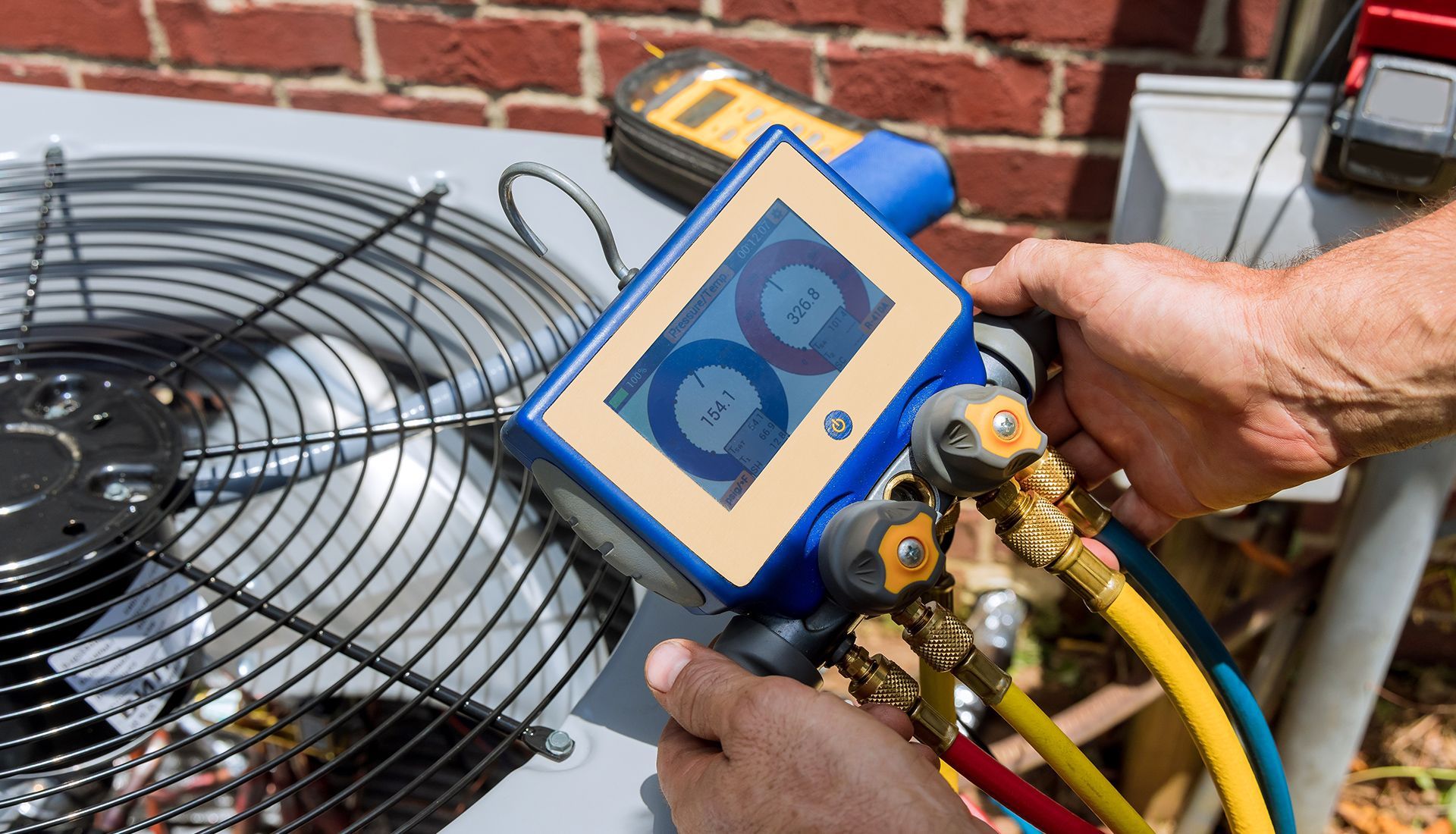 HVAC technician using diagnostic gauges on an outdoor air conditioning unit.