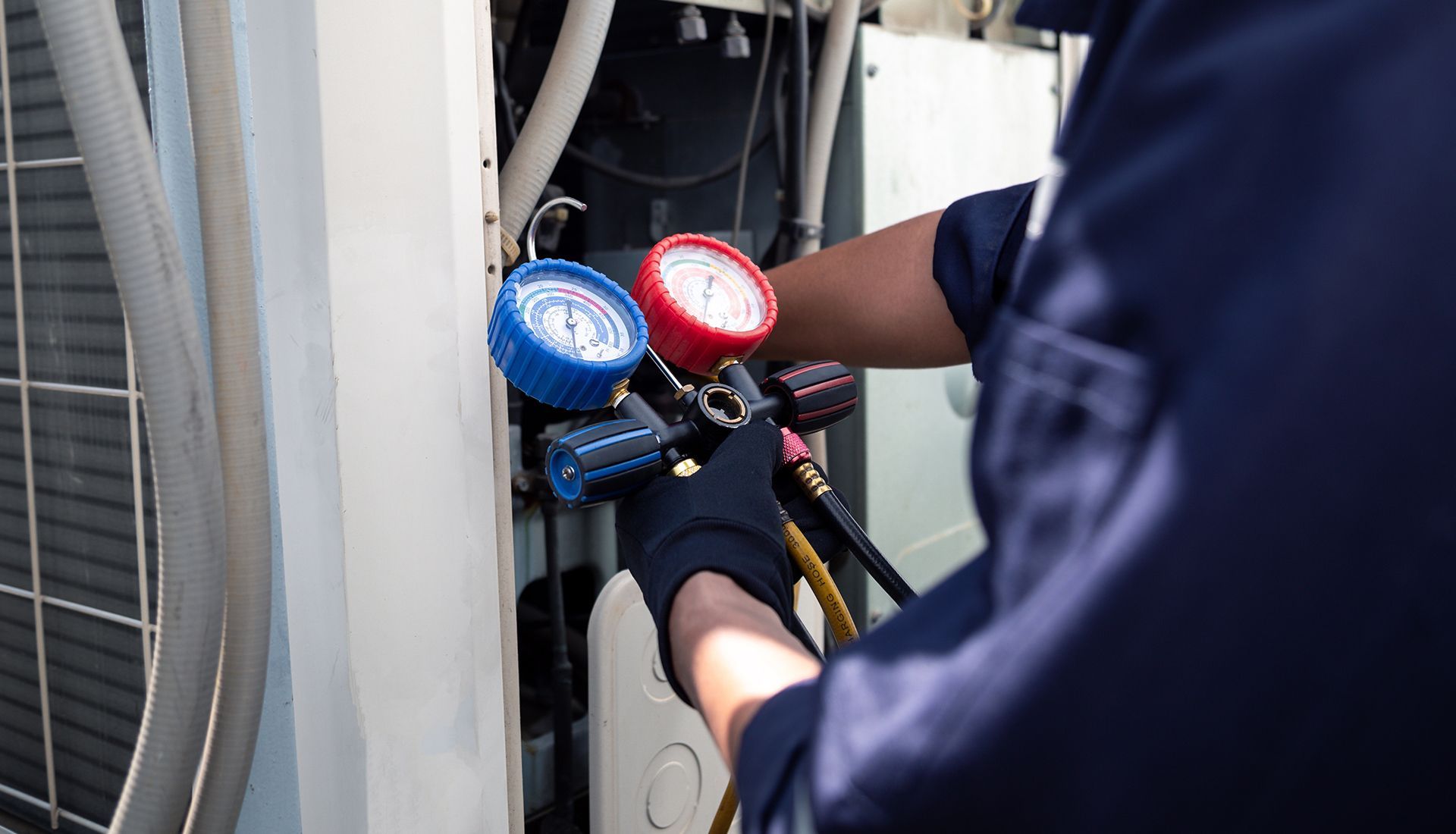 HVAC technician servicing an air conditioning unit using gauges.