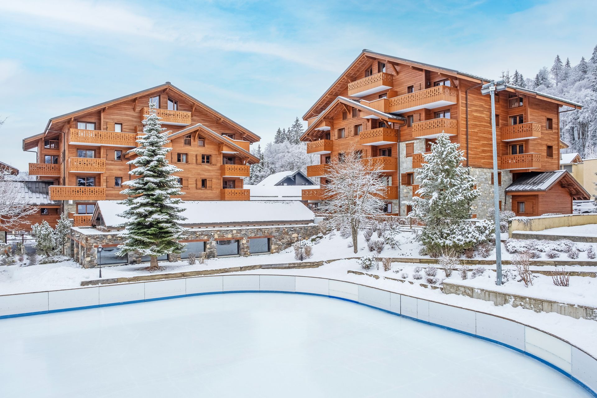 An image of the Les Fermes du Soleil residence from the outside, you can see the buidling and an ice rink in front of it