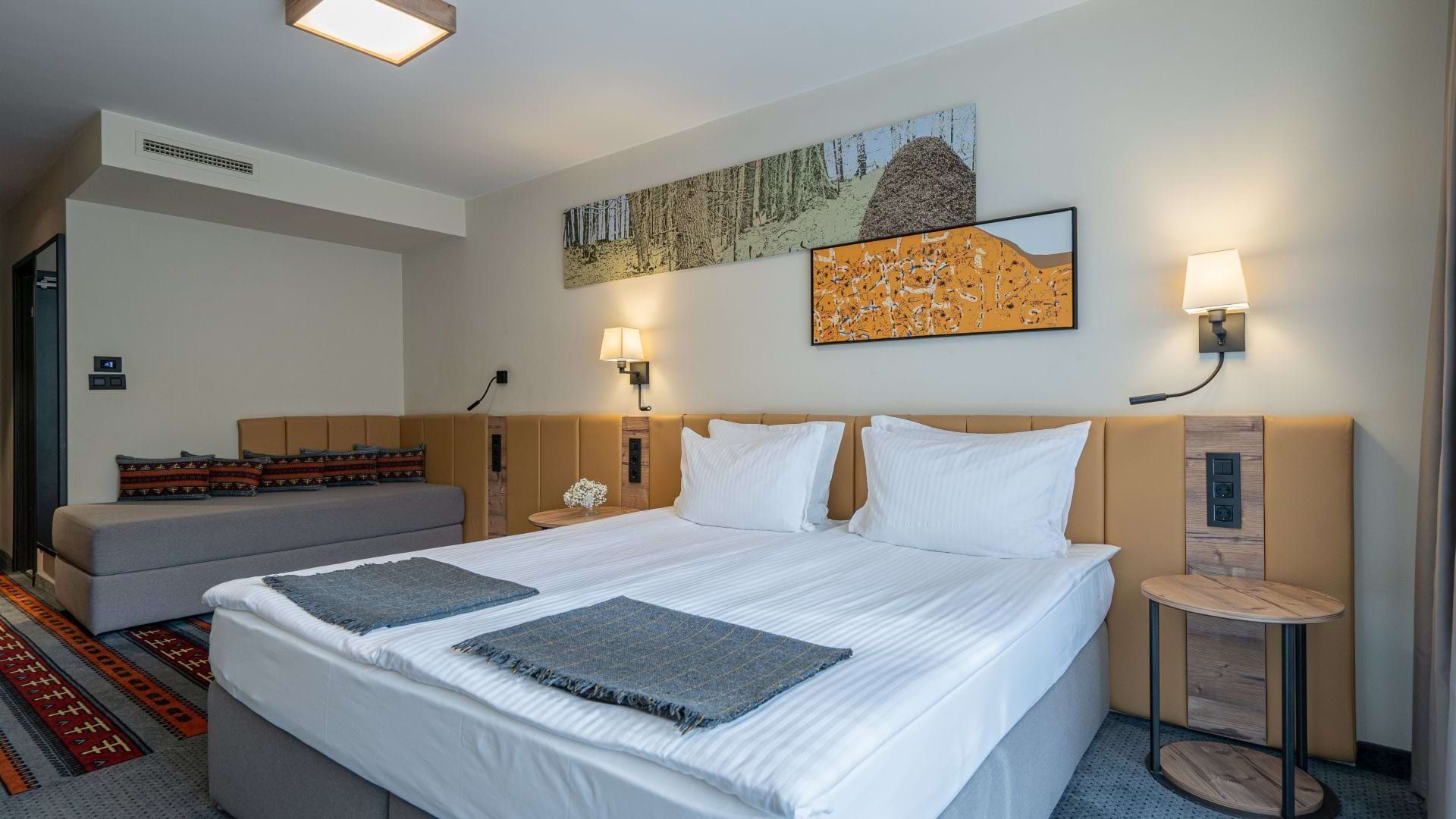 An image of a double bed and a sofa bed in one of the Superior rooms at Hotel Rila