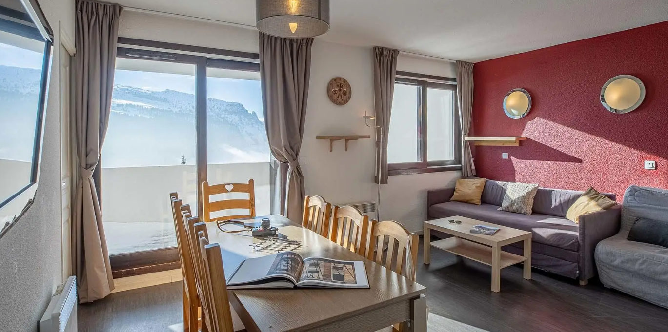 A dining and living area with a balcony and view in the background