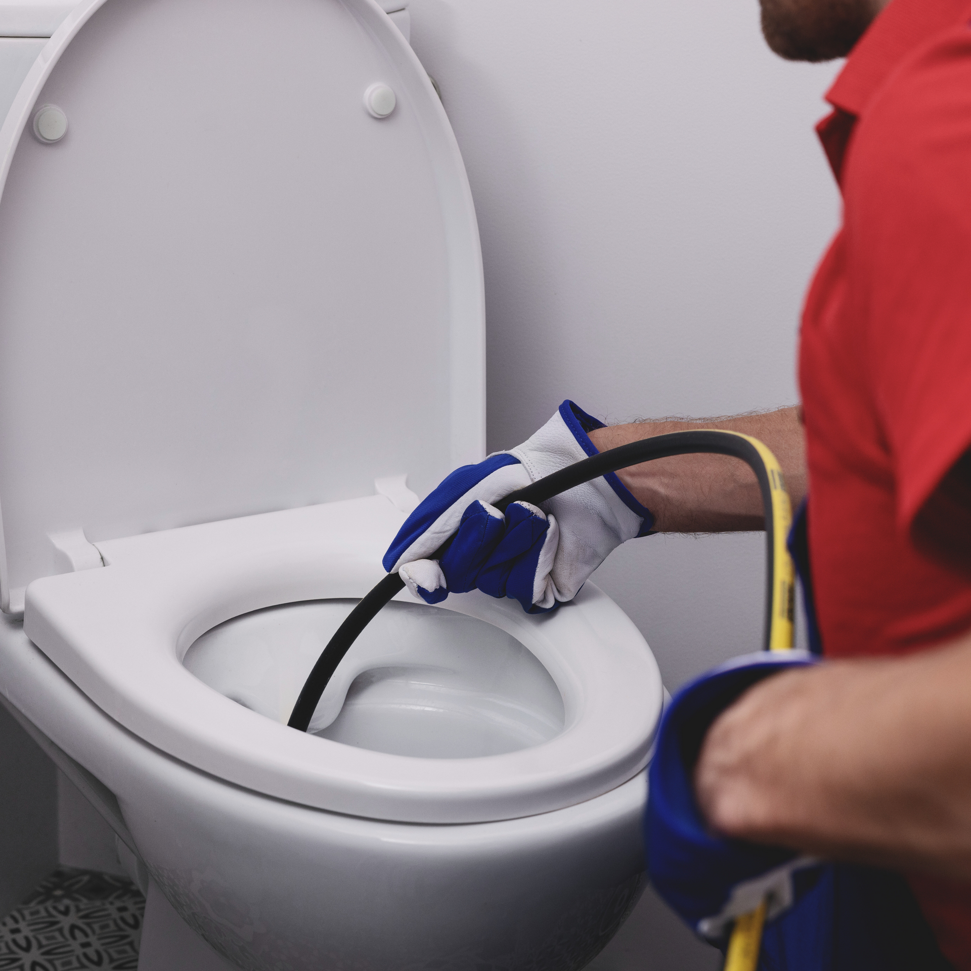 a man in a red shirt is working on a toilet