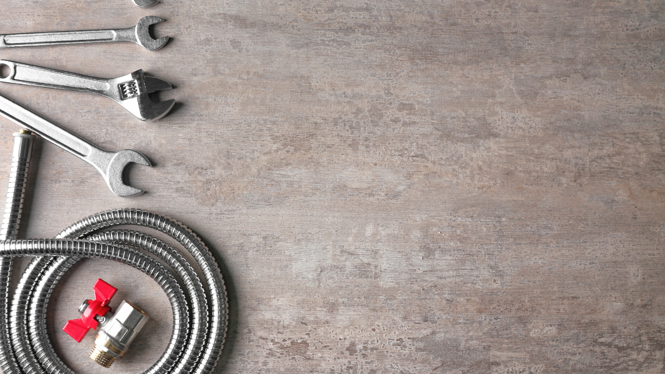 a hose , wrenches , and valves are on a table .