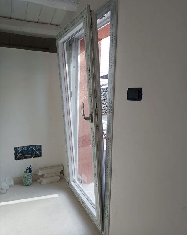 Una stanza con una porta scorrevole in vetro e una parete bianca.