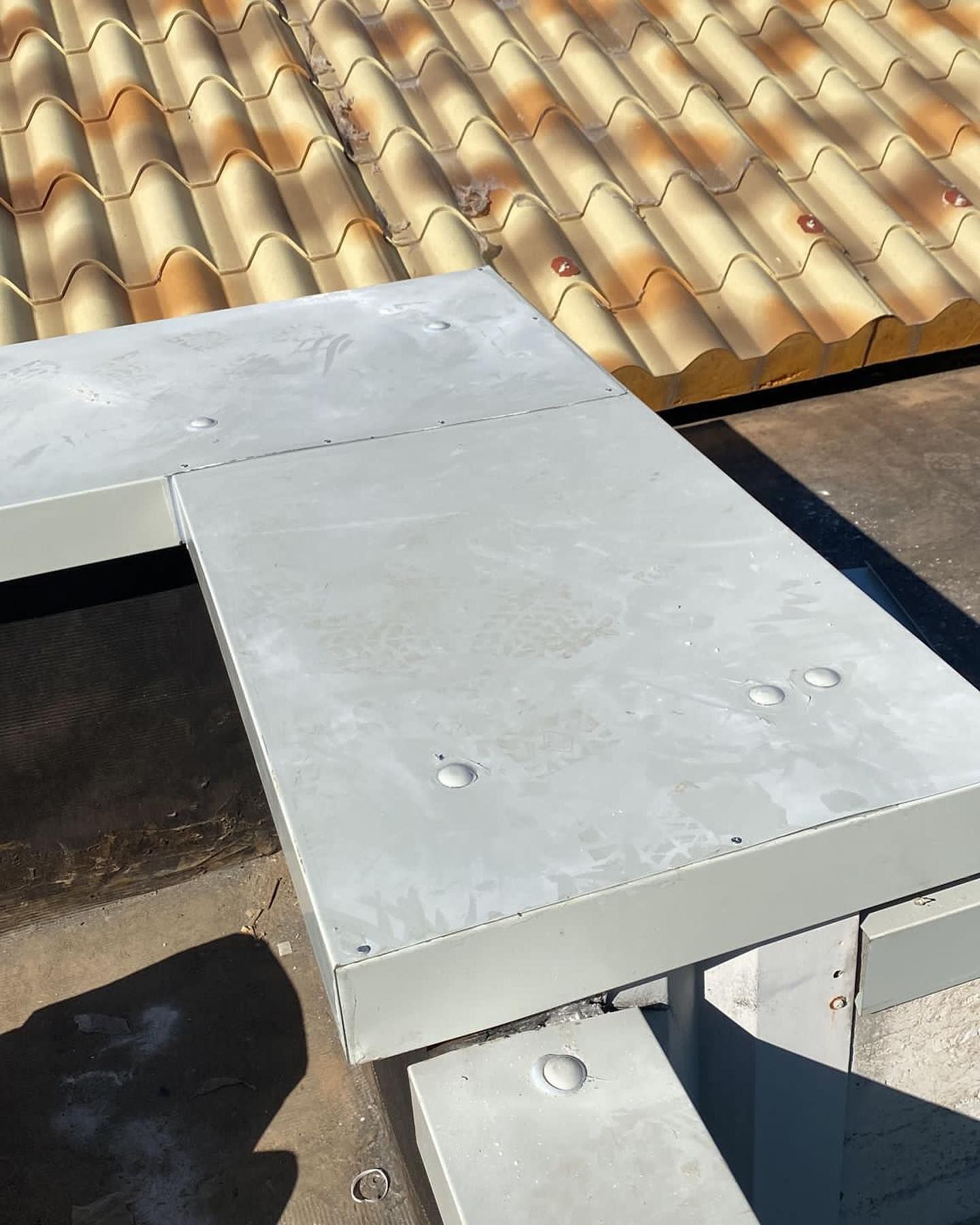 Un tetto di tegole è dietro una sporgenza di cemento