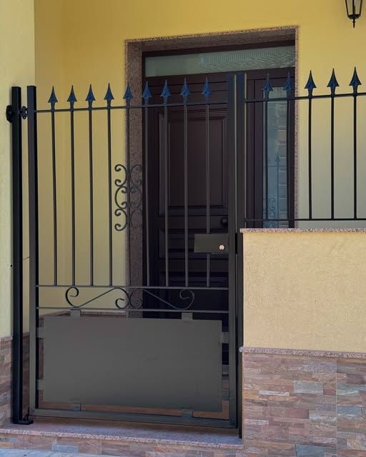 Un edificio giallo con un cancello nero che conduce a una porta