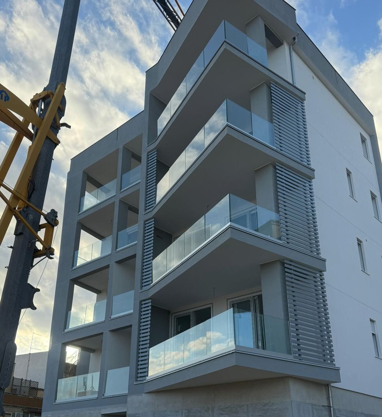 Un edificio con molti balconi e una gru sullo sfondo