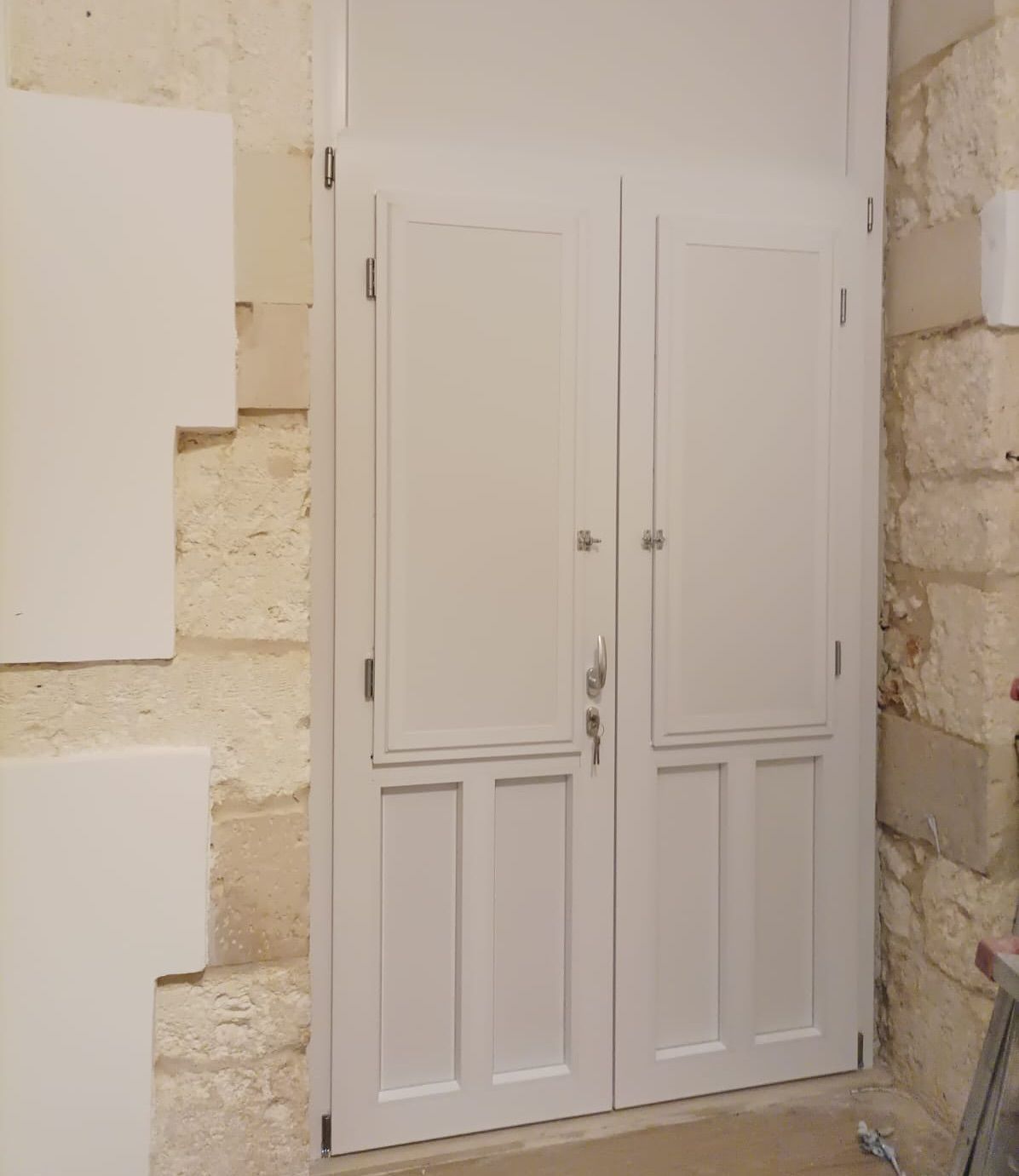 Una porta bianca con una chiave dentro è accanto a un muro di pietra