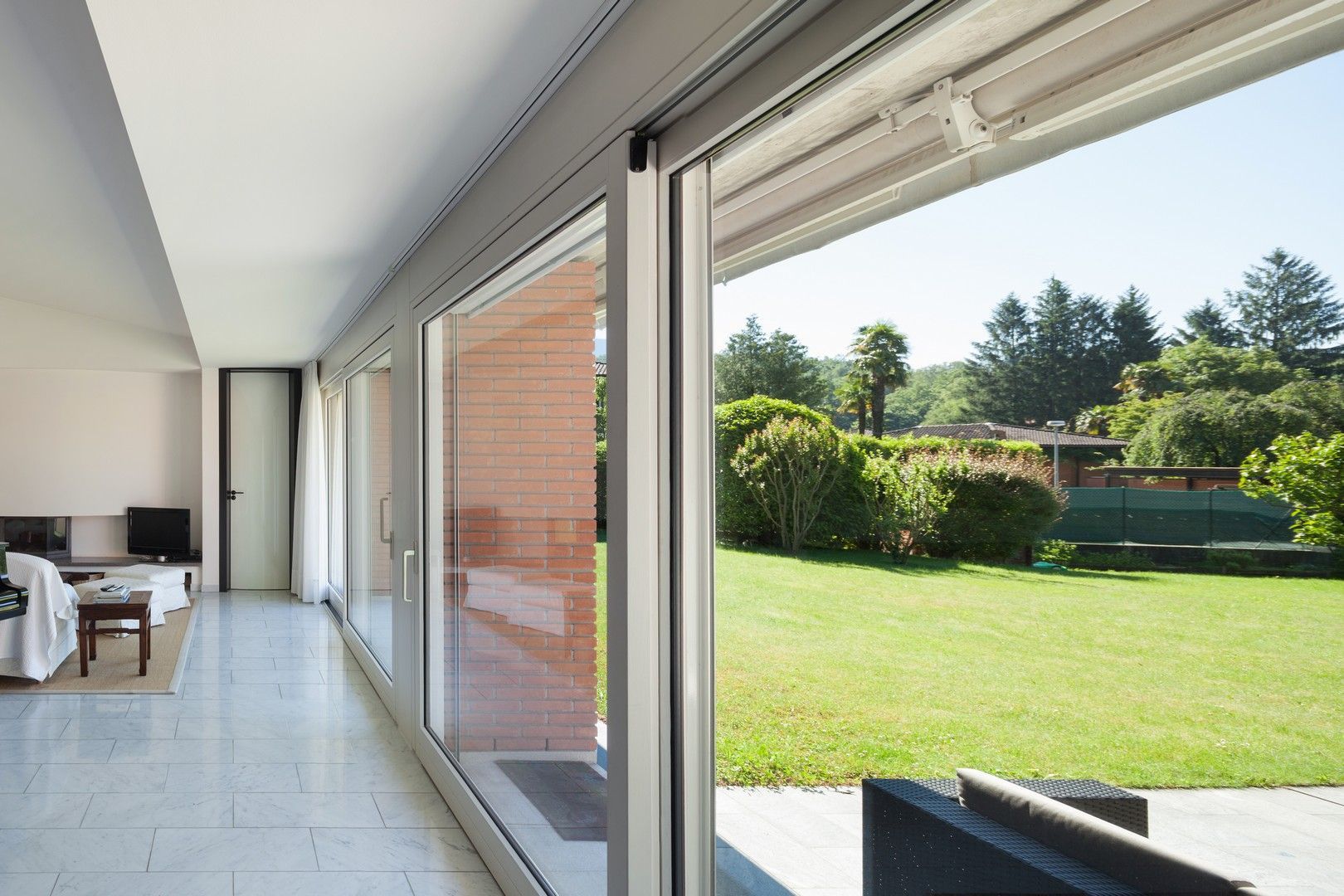 Un soggiorno con molte finestre e un prato sullo sfondo.