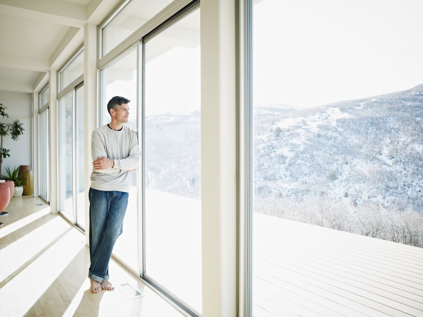 Un uomo è in piedi davanti a una grande finestra e guarda fuori.
