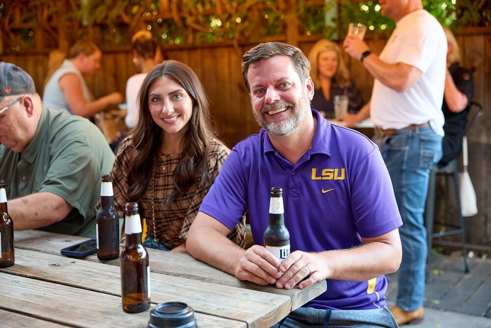 A man and a woman are sitting at a table with bottles of beer.