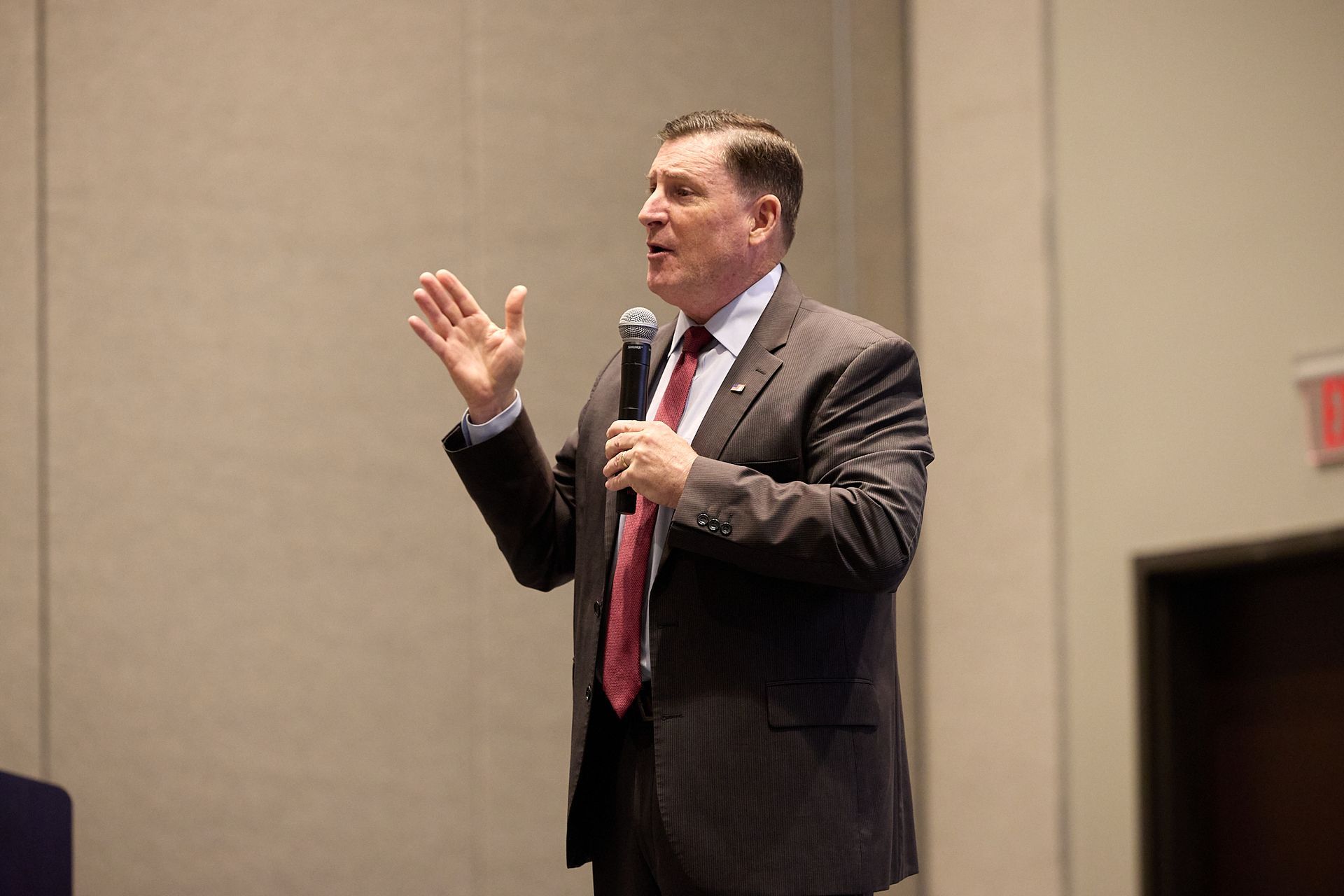 A man in a suit and tie is speaking into a microphone.