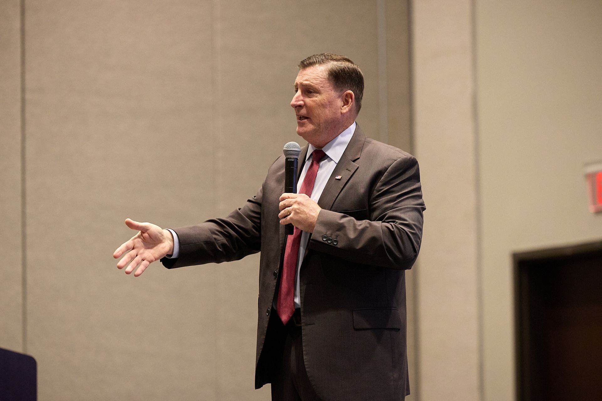 A man in a suit and tie is speaking into a microphone.