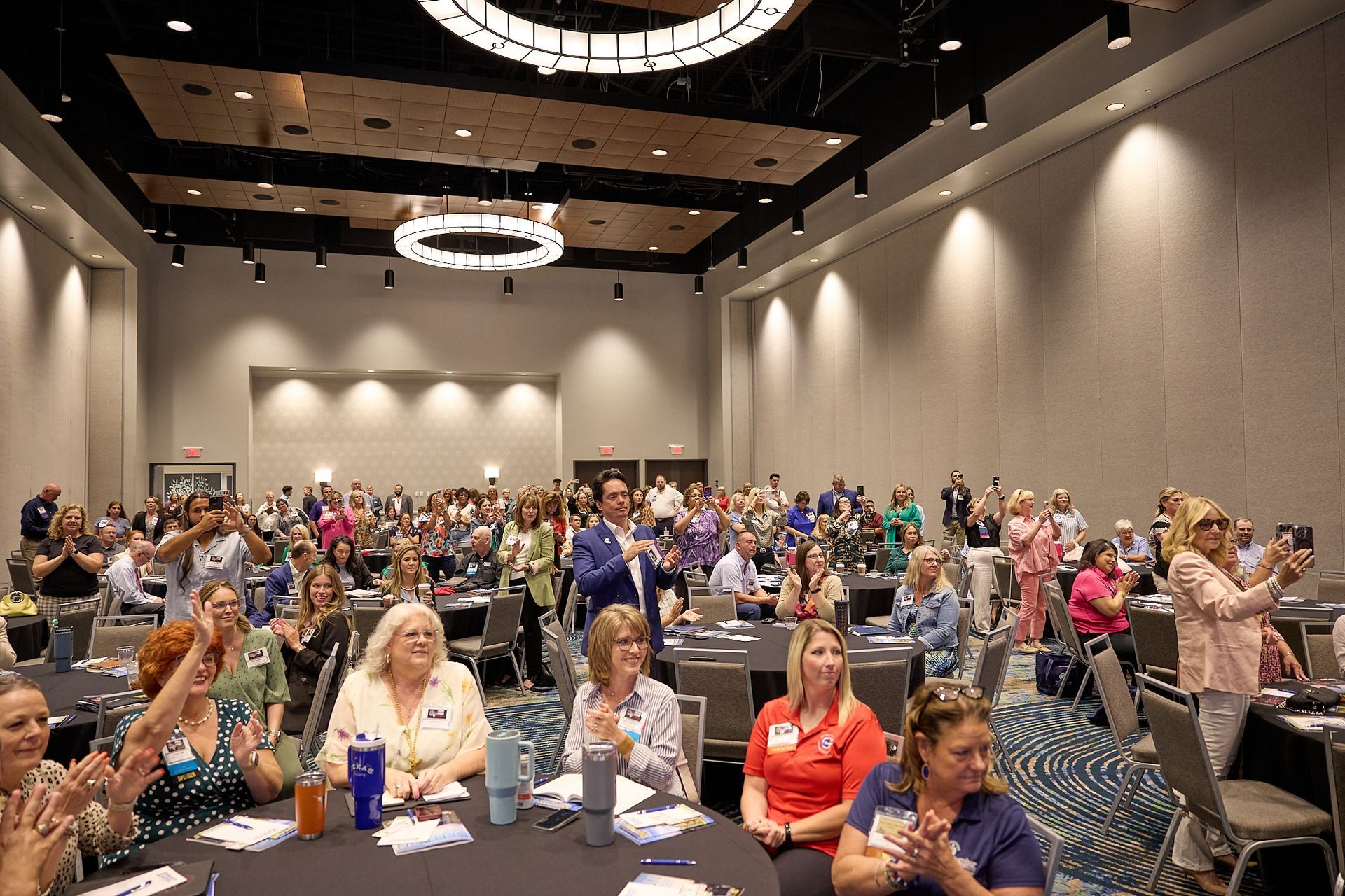 A large group of people are sitting at tables in a large room.