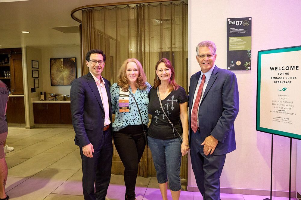 A group of people are posing for a picture in front of a welcome sign.