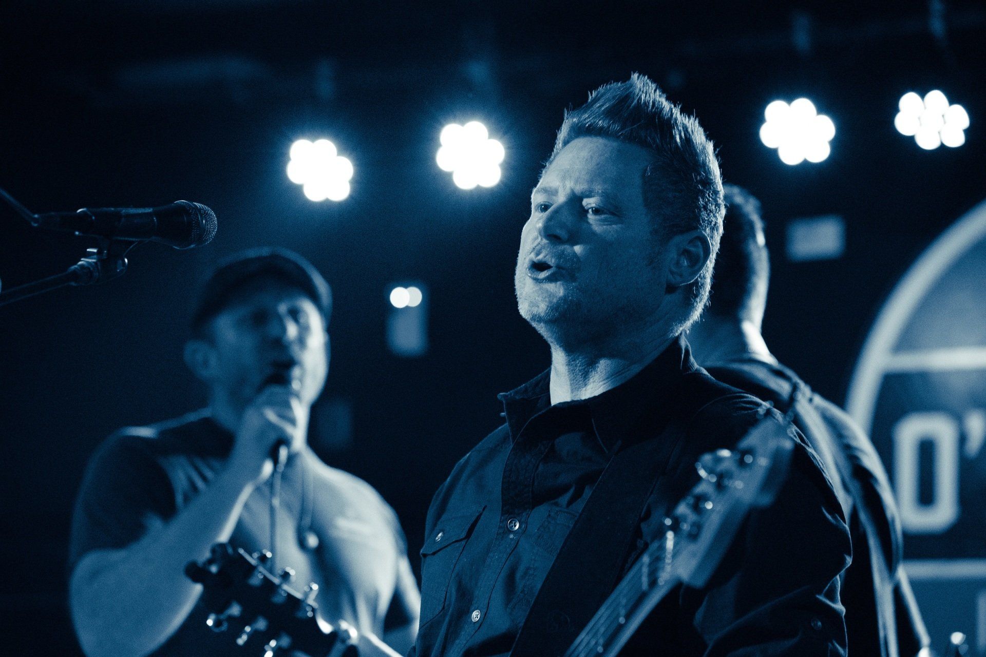 A man singing into a microphone while playing a guitar