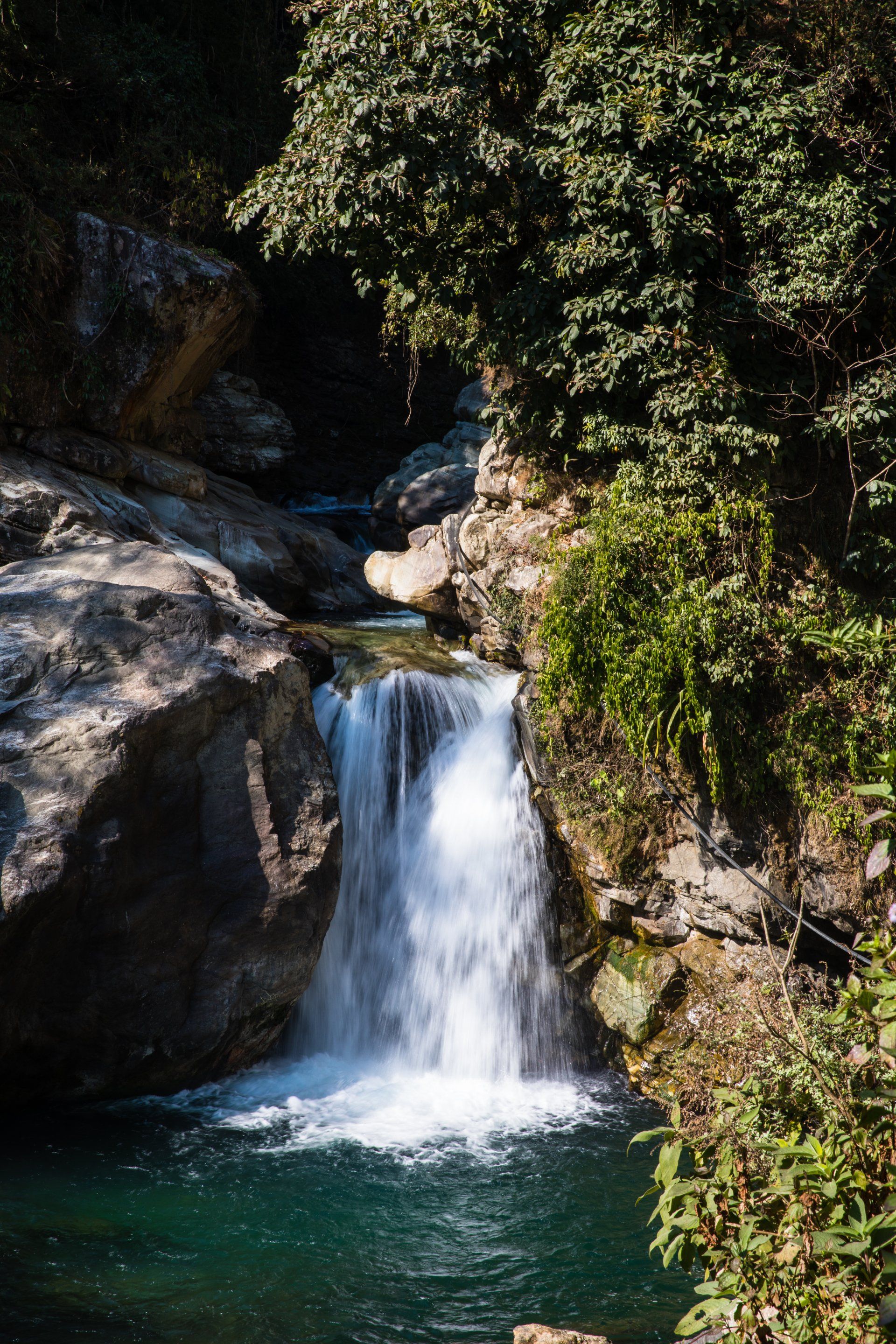 A waterfall is surrounded by trees and rocks in the middle of a forest.