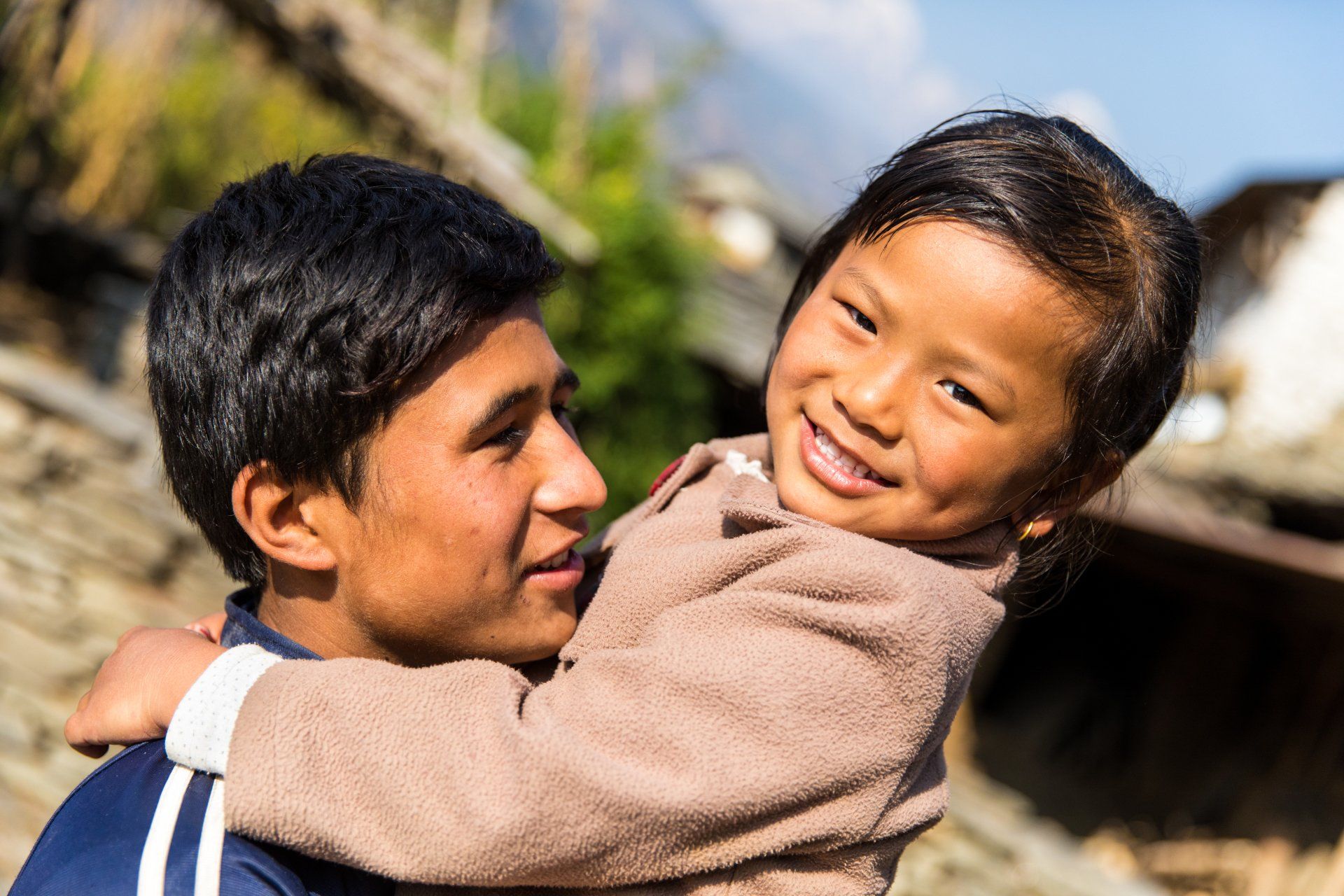 A brother is holding his sister in his arms.
