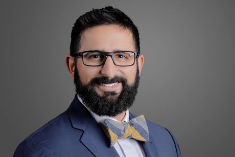 A man with a beard is wearing glasses and a bow tie.