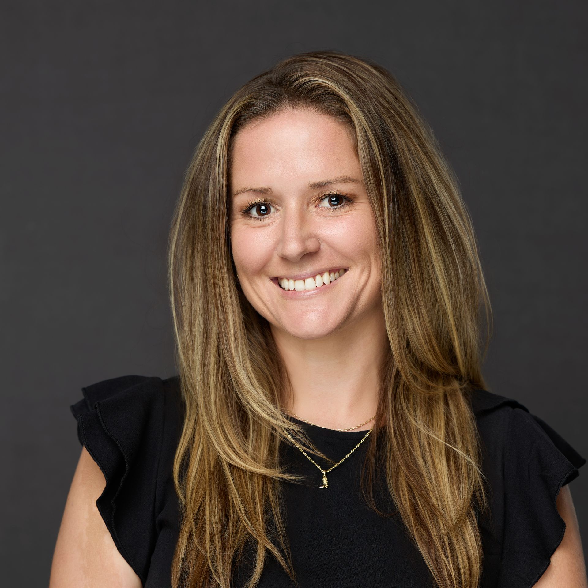 A woman with long hair is smiling and wearing a black shirt
