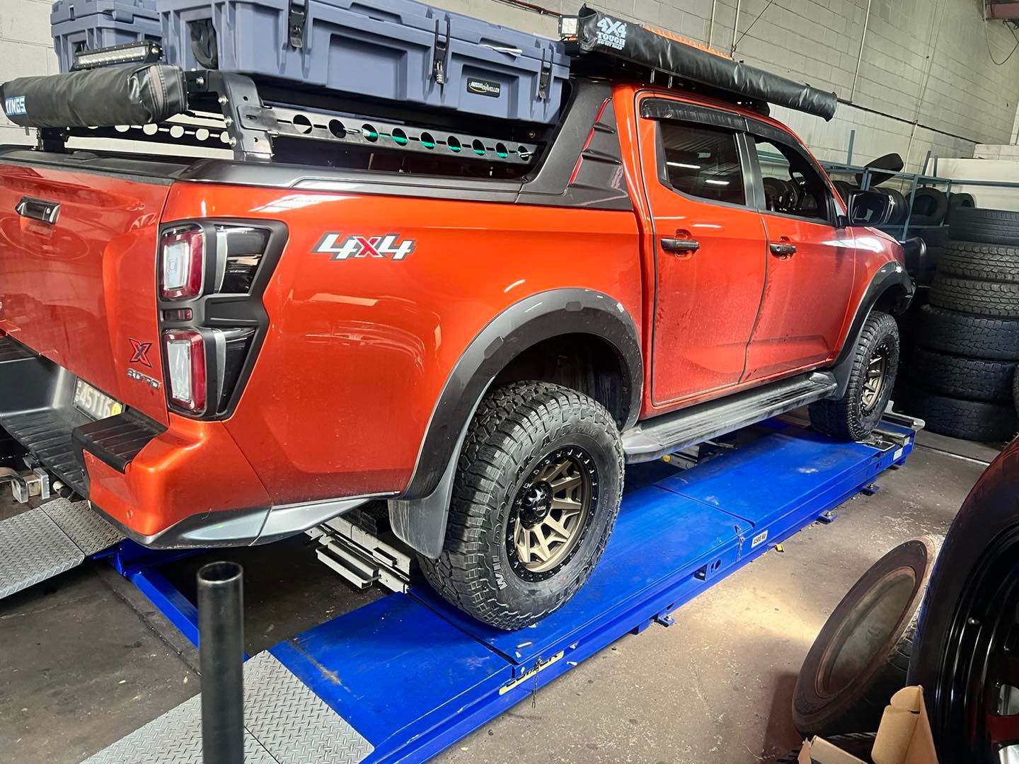 A red truck is sitting on top of a blue lift in a garage.