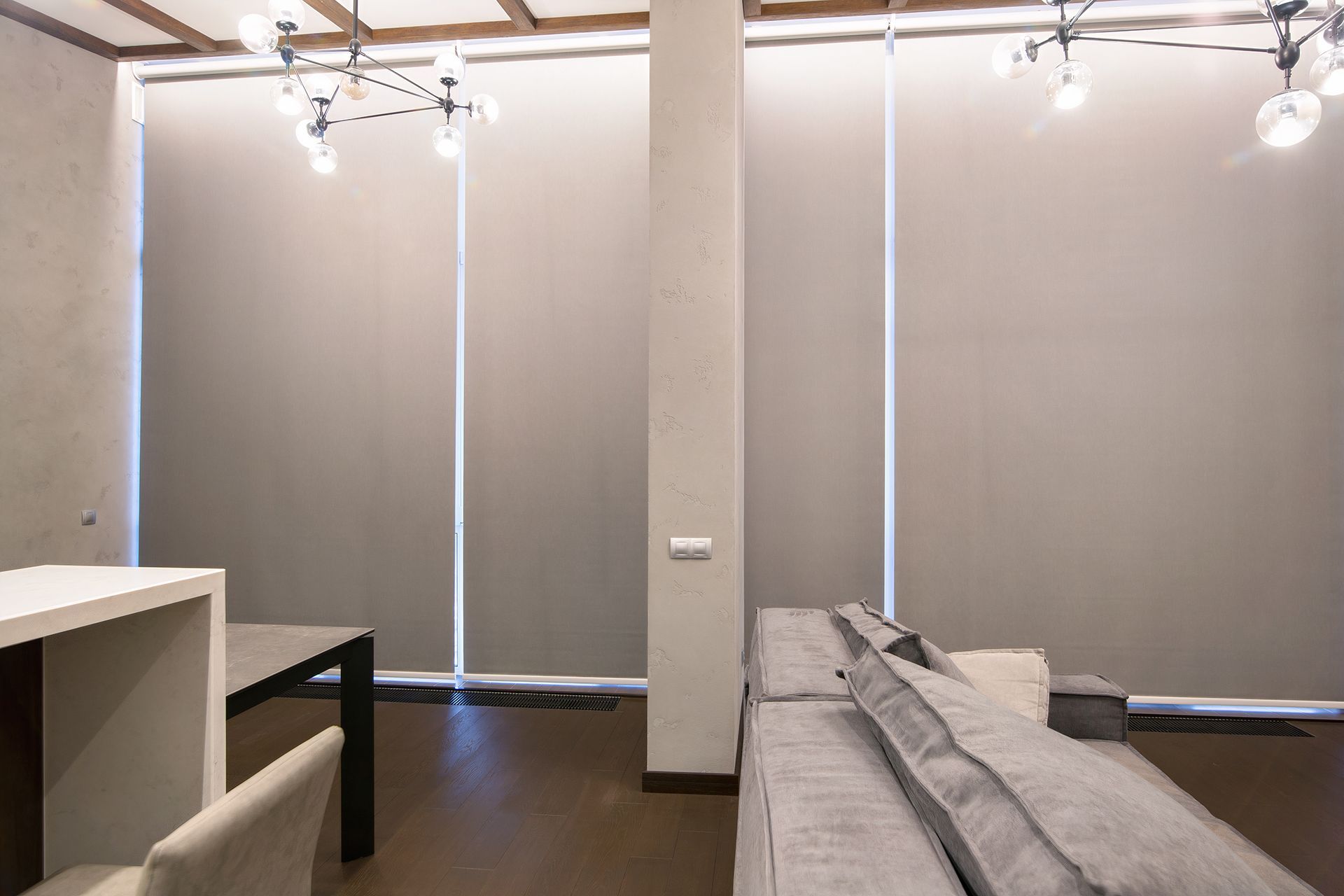 A living room with a couch , table , chairs and blinds on the windows