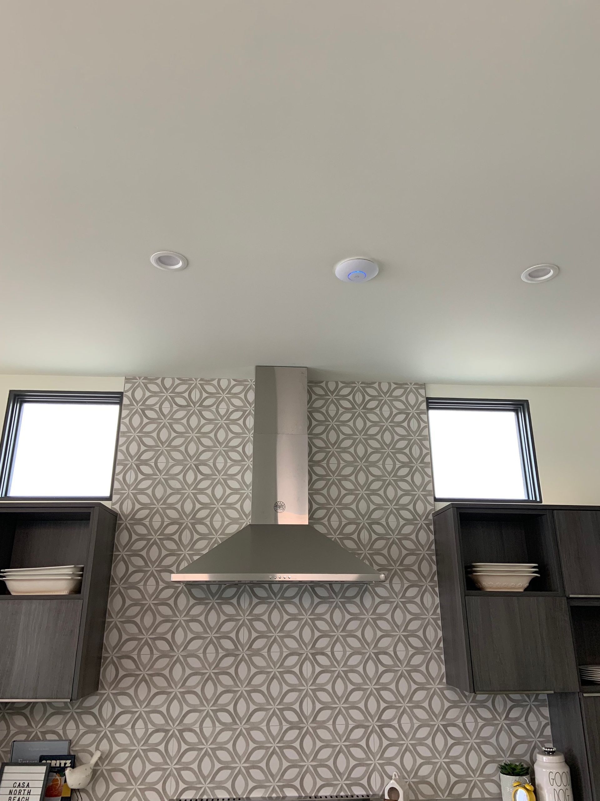 A stainless steel hood is hanging from the ceiling in a kitchen