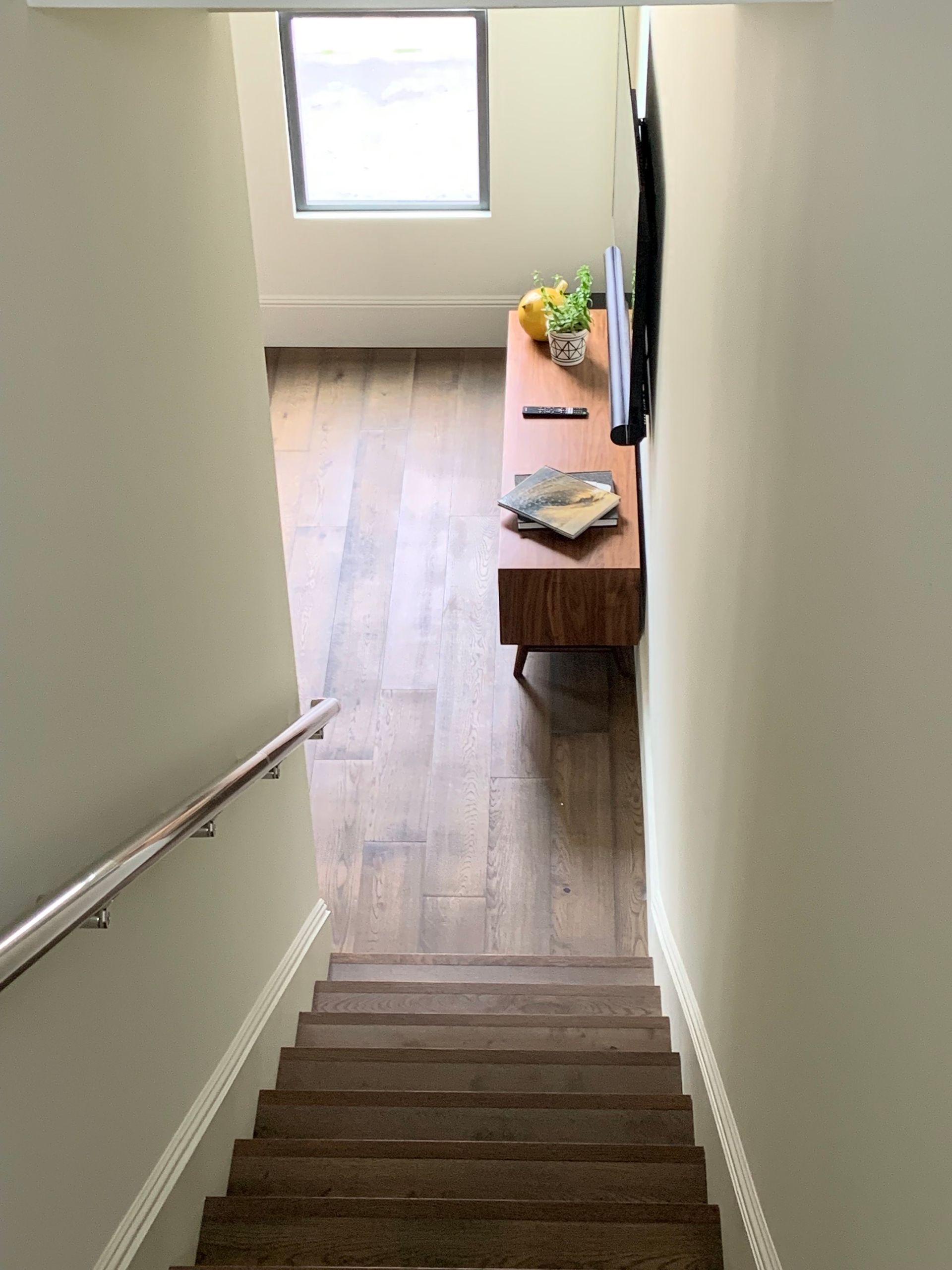 A staircase leading up to a living room with a television on the wall