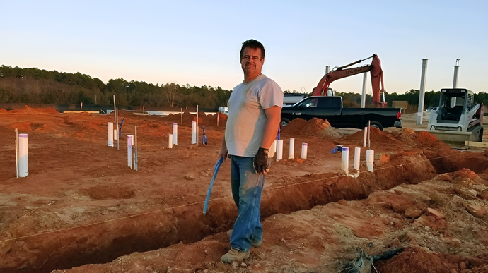 A man in a white shirt is standing in a dirt field