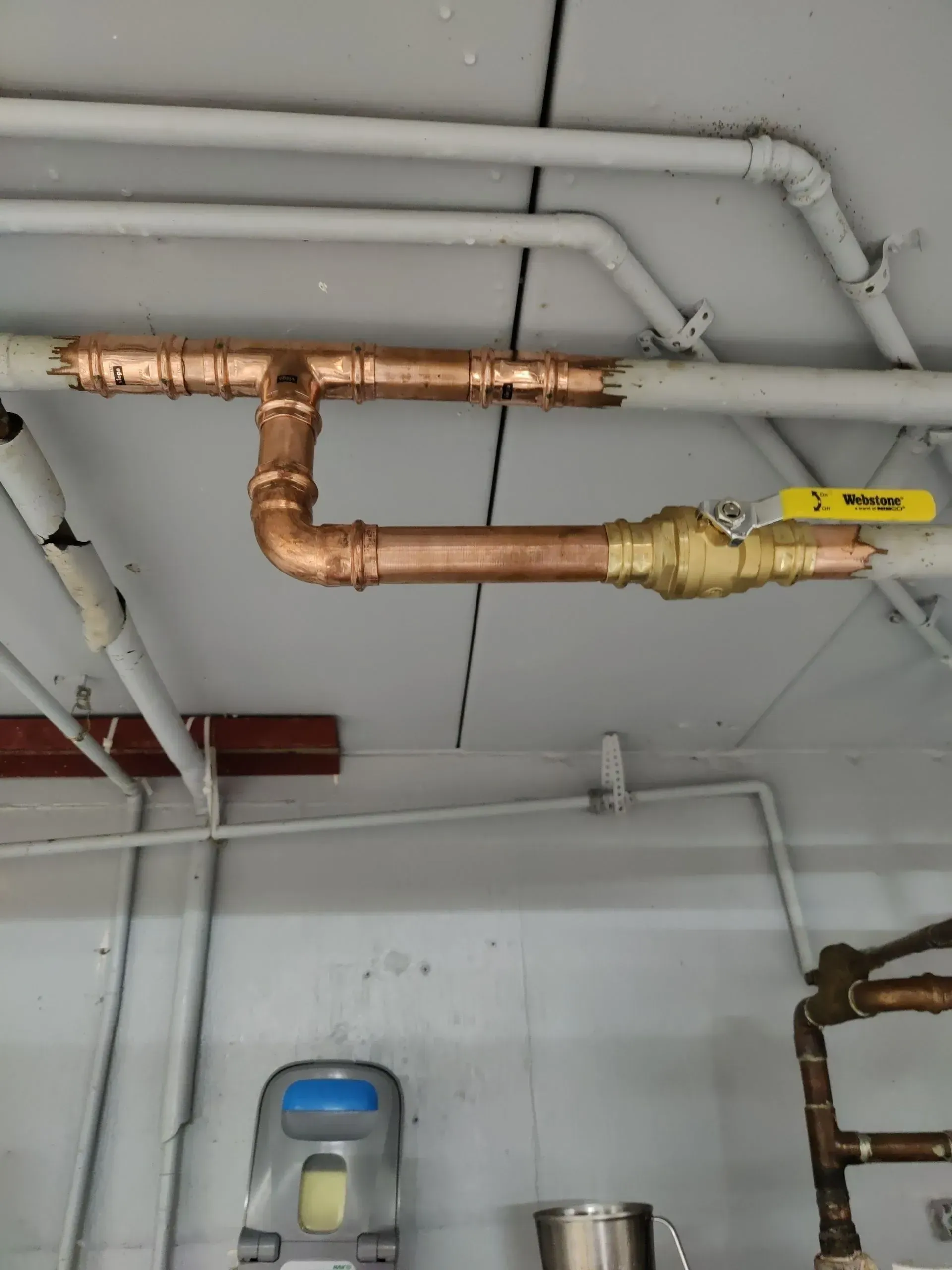 A room with copper pipes and a yellow valve.