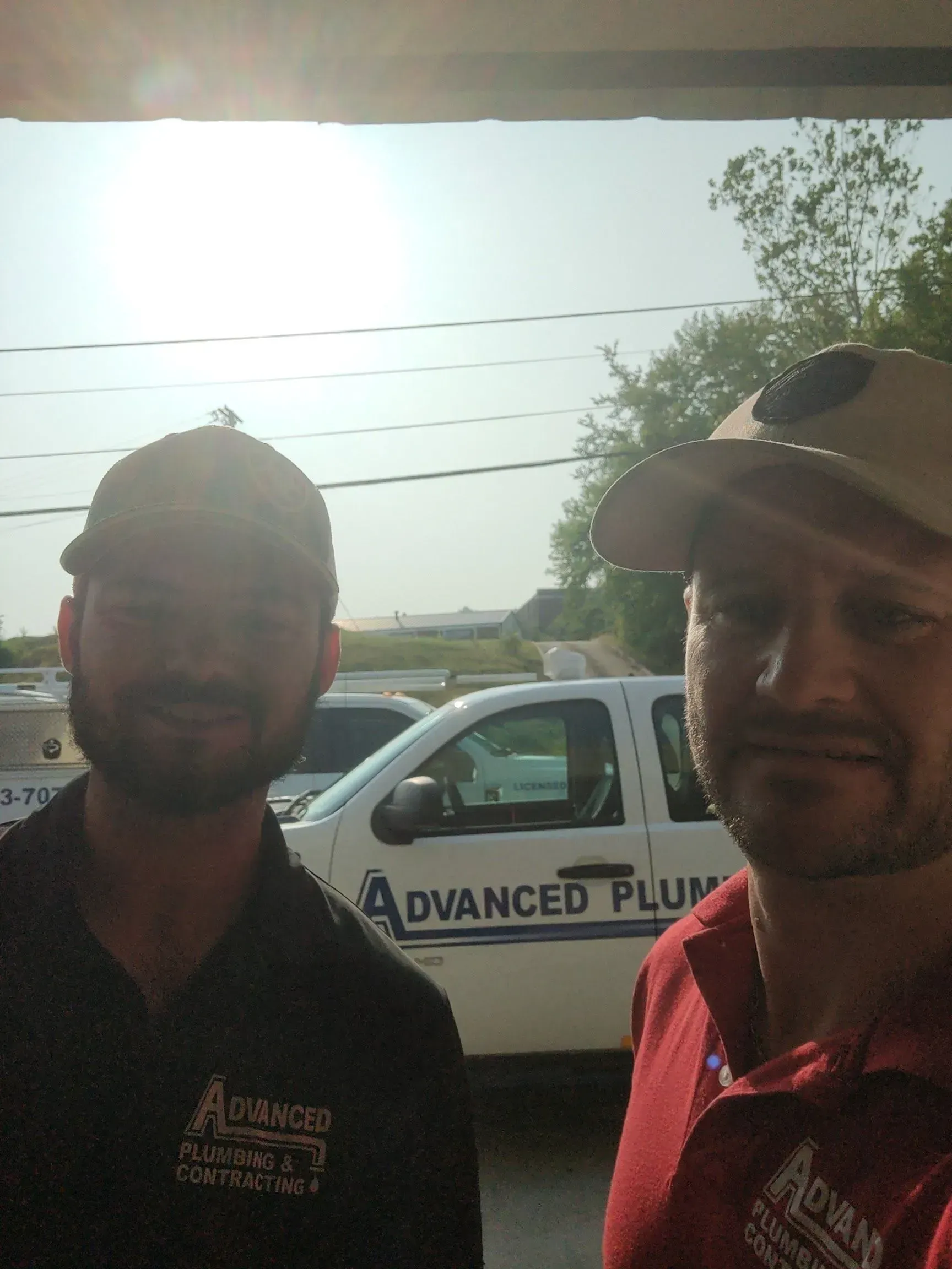 Two men are standing in front of an advanced plumbing truck