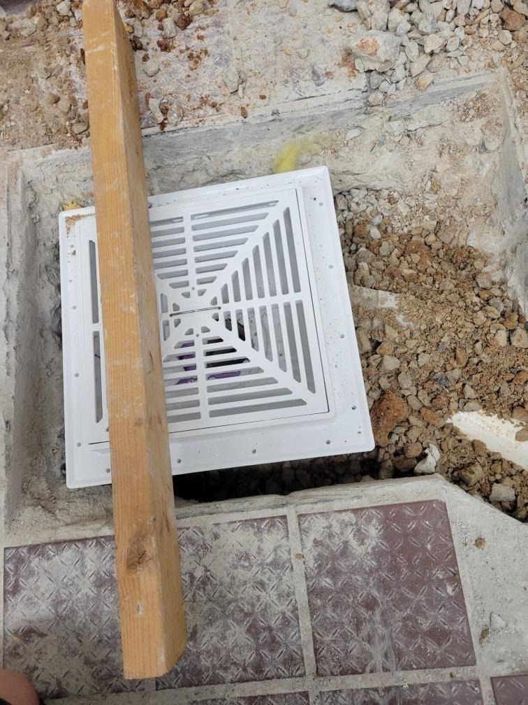 A wooden plank is sitting next to a white vent