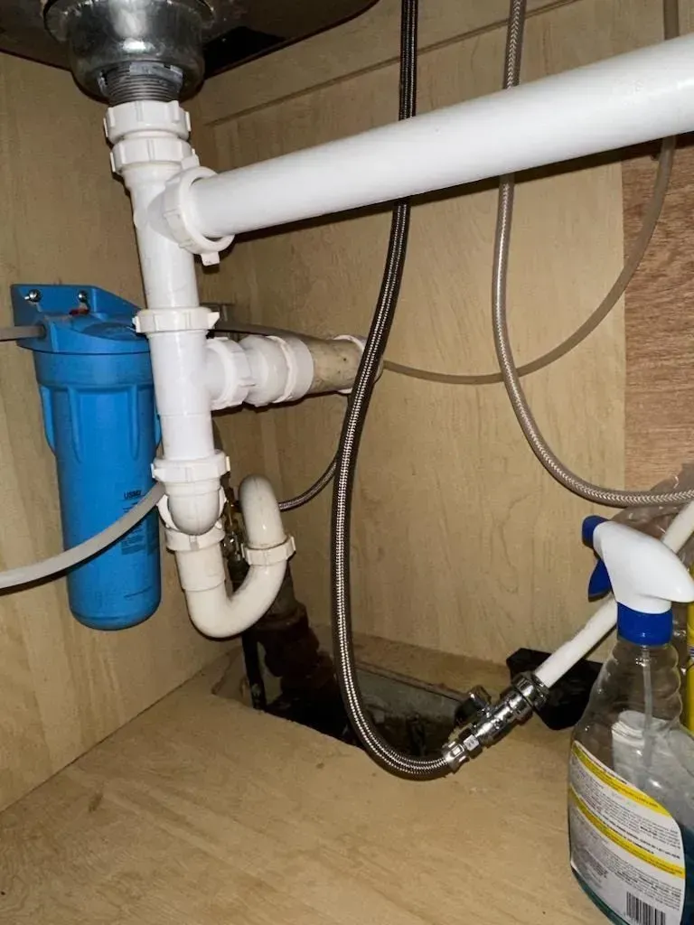 A sink with a blue filter and a spray bottle underneath it
