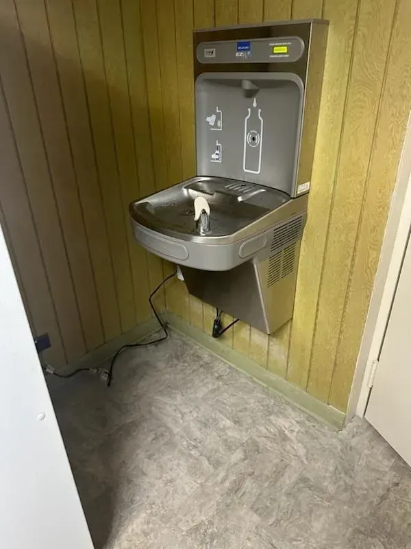 A water fountain is mounted to the wall in a room.