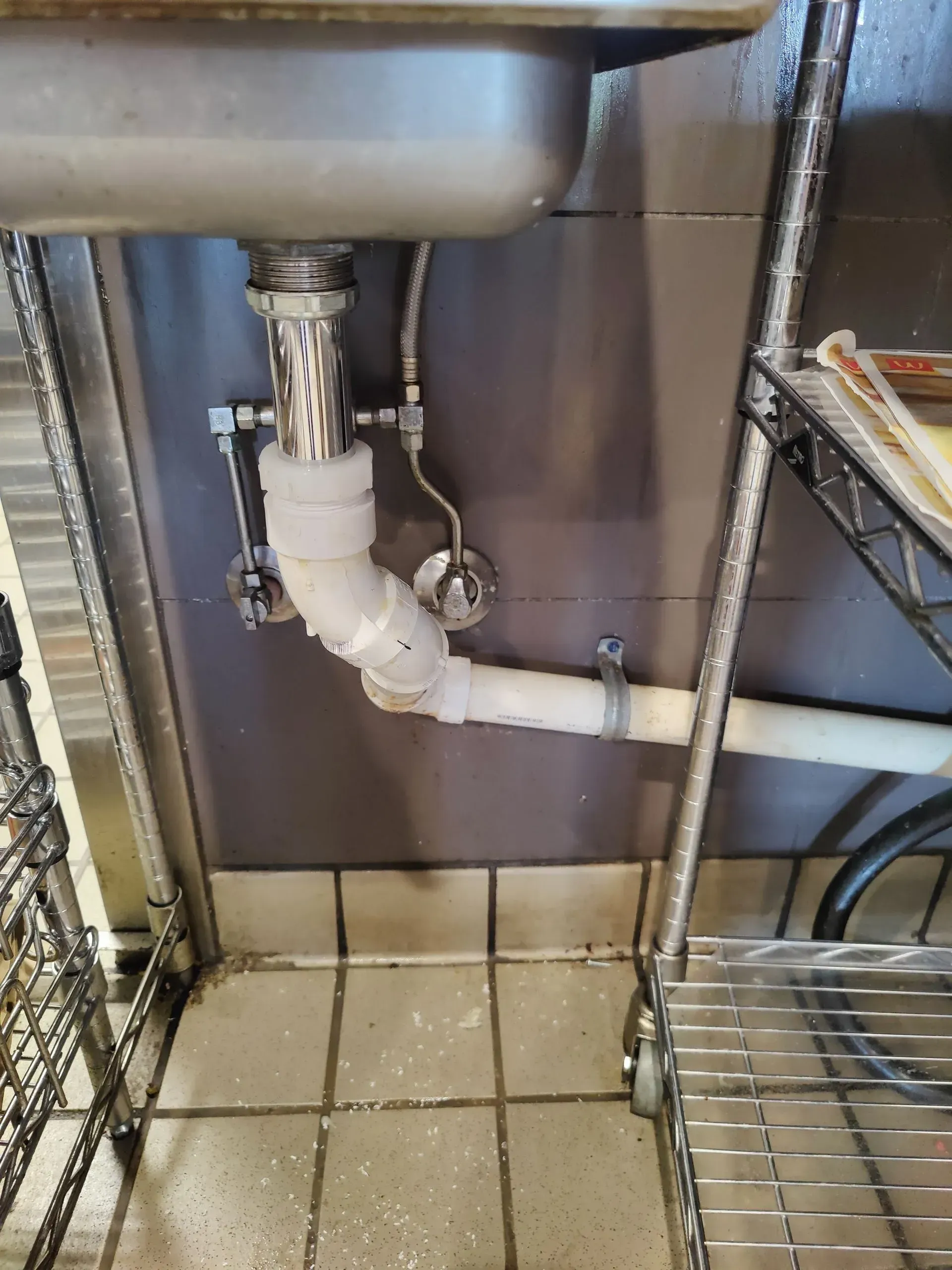 A sink with a pipe underneath it in a kitchen.