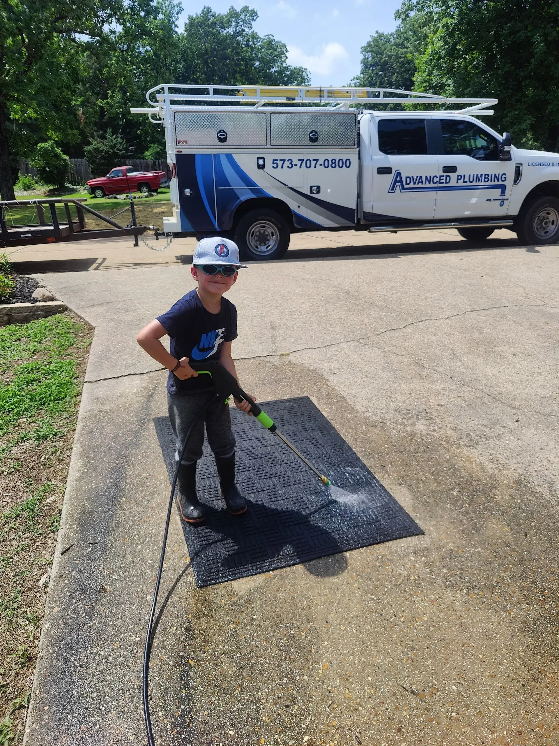 A young boy is cleaning a sidewalk in front of a truck.