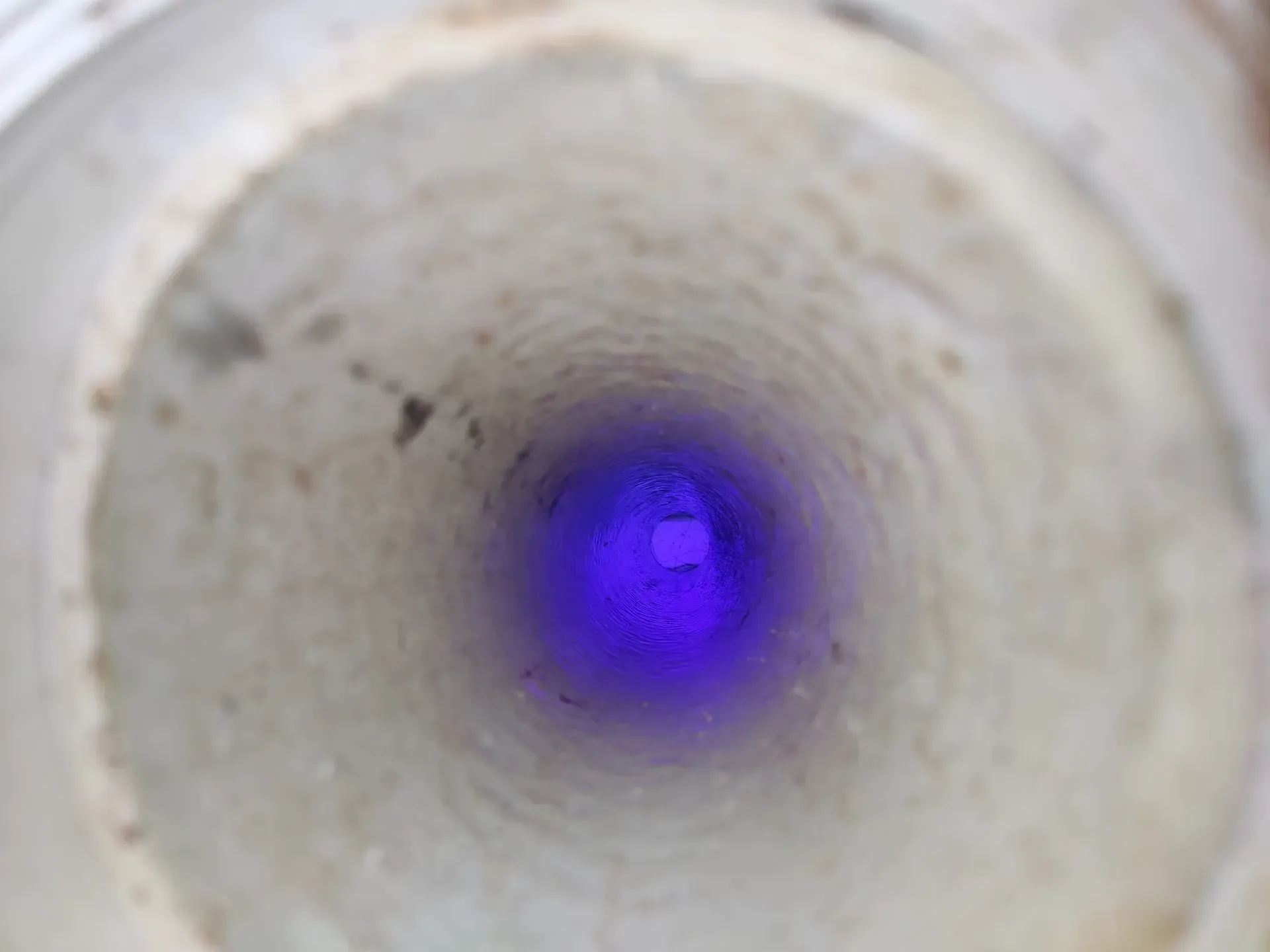 A purple light is shining through a hole in a pipe.