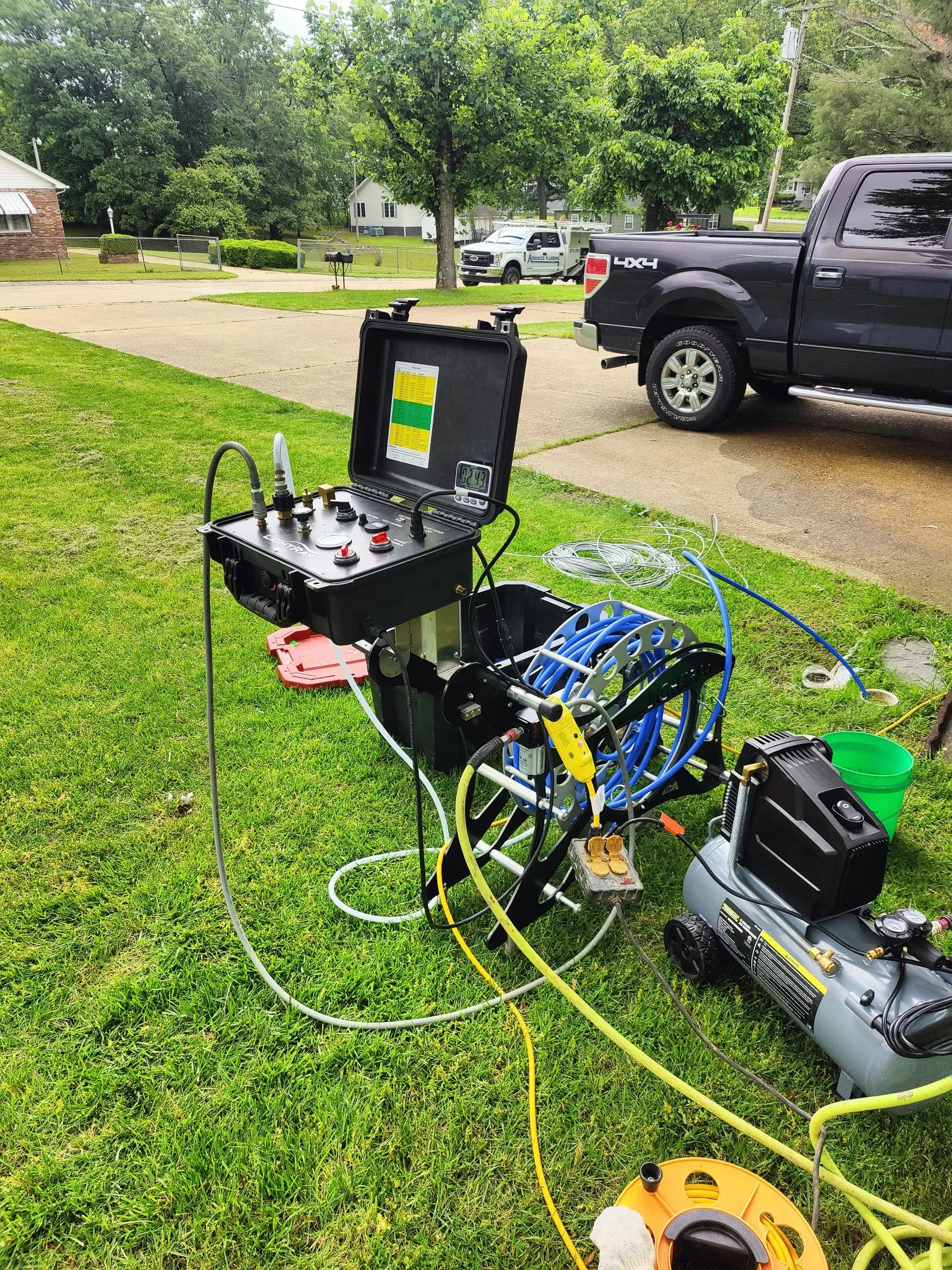 A truck is parked in the grass next to a table with tools on it.