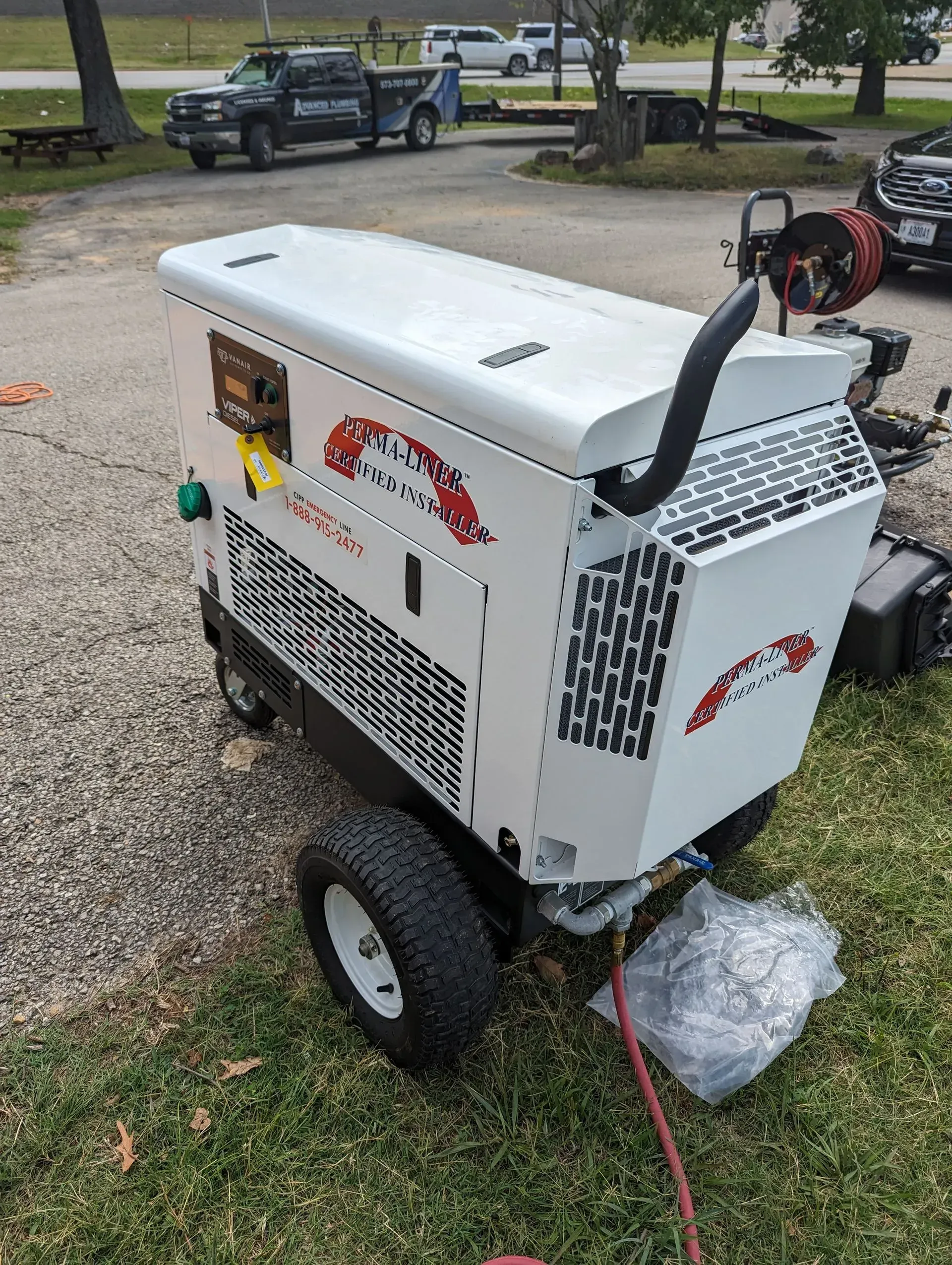A white machine is sitting on the grass next to a truck.