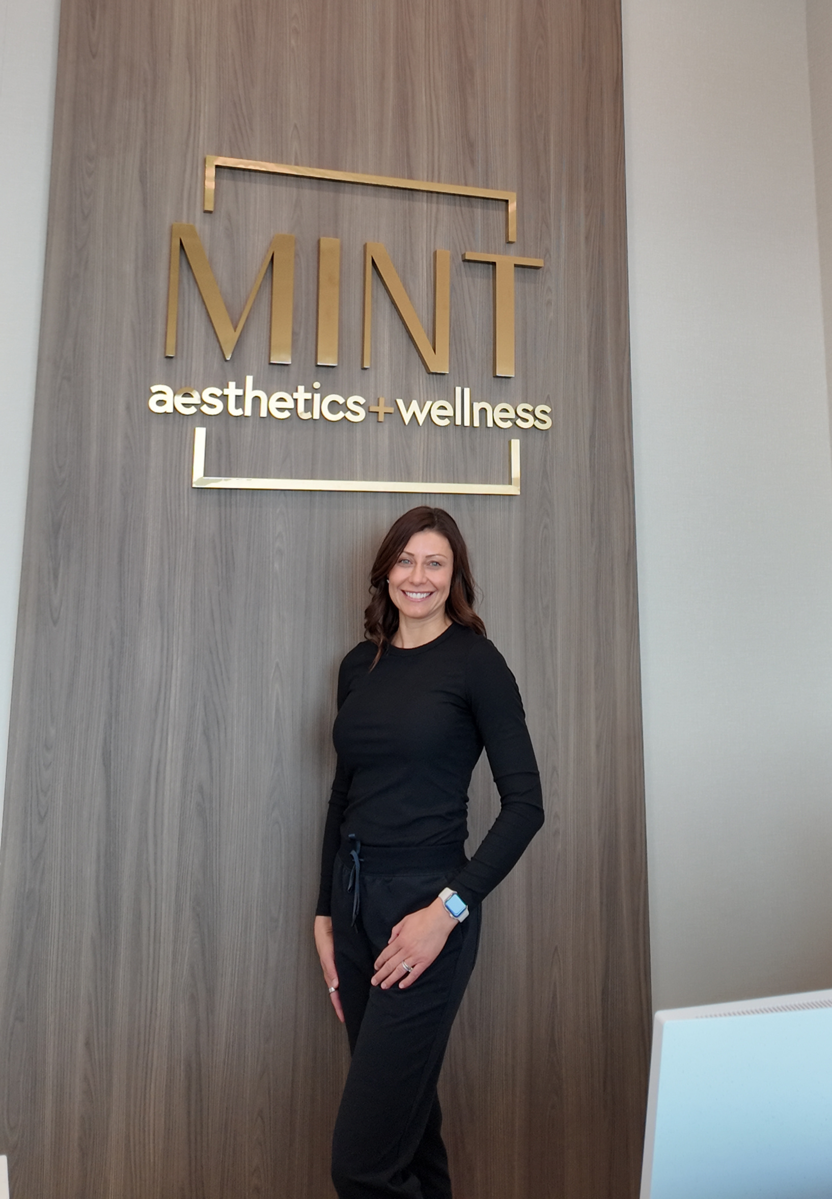 A woman in a green shirt and black pants is sitting on a porch.