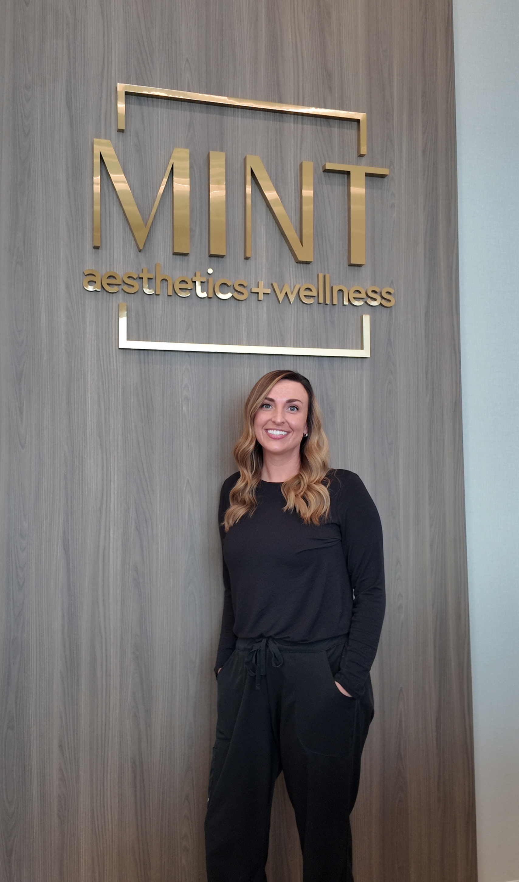 A woman in a green shirt and black pants is sitting on a porch.