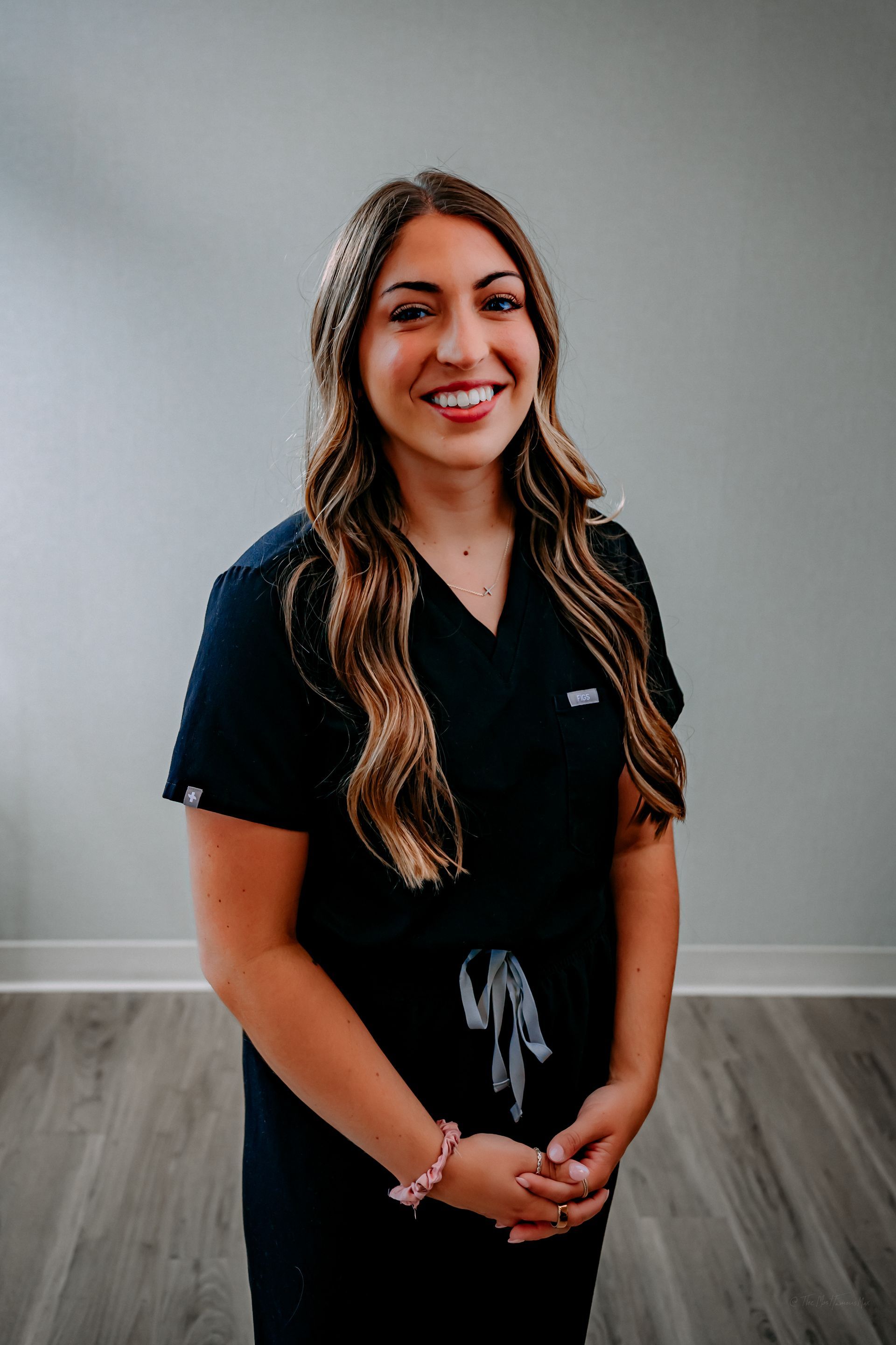 A woman in a black turtleneck is smiling for the camera while standing on a porch.
