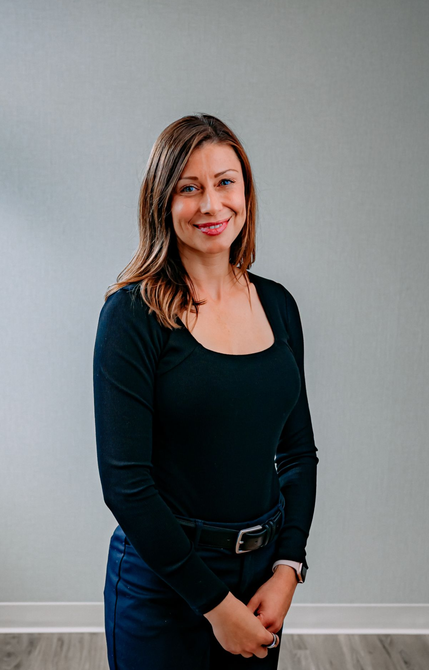 A woman in a green shirt and black pants is sitting on a porch.