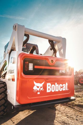 A bobcat skid steer is parked in the dirt on a dirt road.